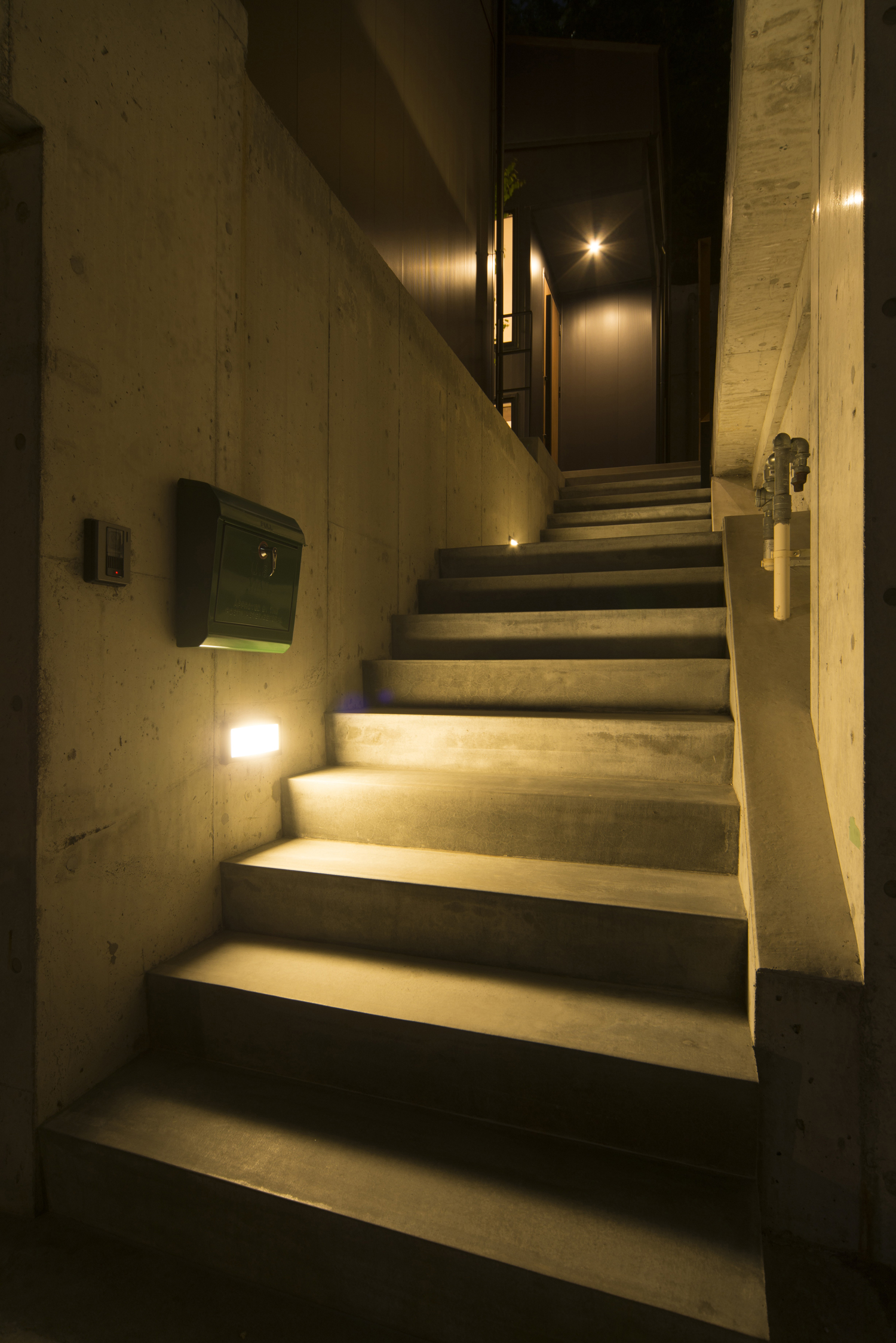 足元に照明を取り付けたコンクリートの階段アプローチ・デザイン住宅