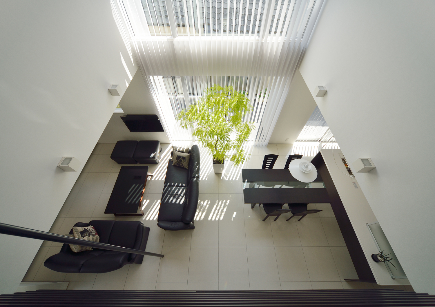 吹き抜けから白いタイルと黒いインテリアのLDKを見下ろした様子・デザイン住宅