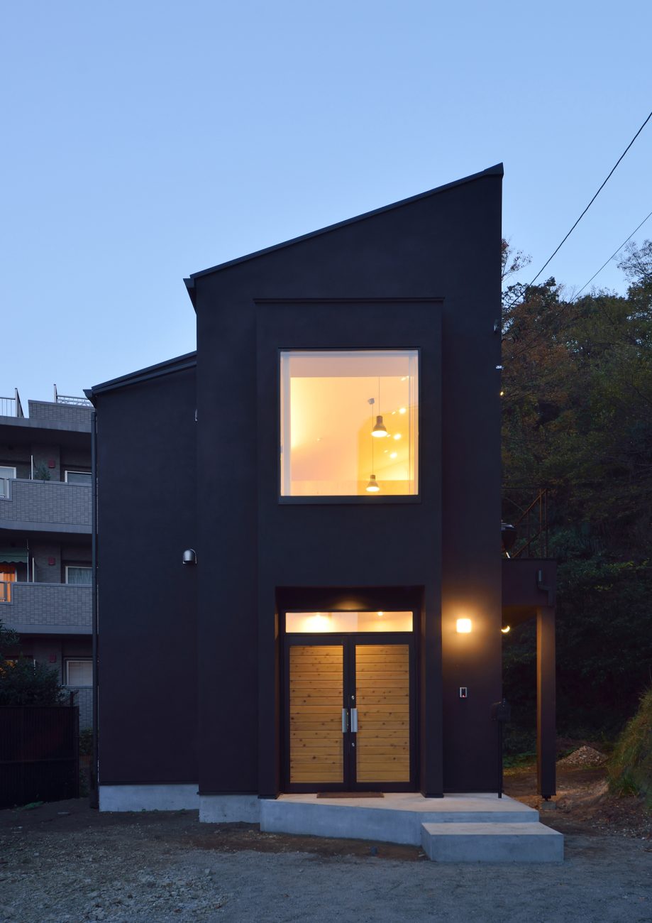 正方形の窓がある黒い外壁の斜め屋根の家・デザイン住宅