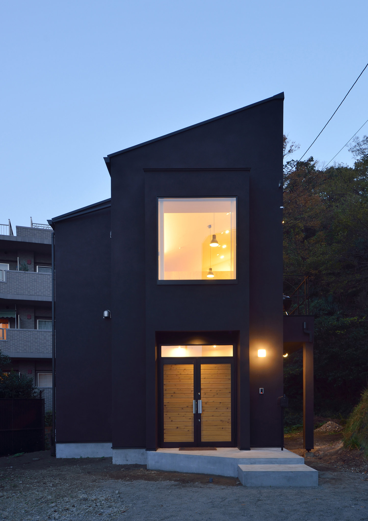 正方形の窓がある黒い外壁の斜め屋根の家・デザイン住宅