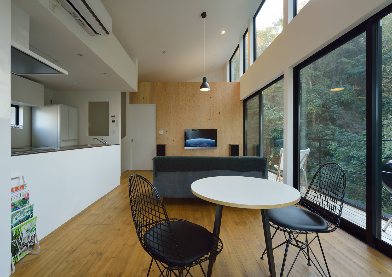 バルコニーに面した大きな窓や木の壁がある自然が感じられるLDK・デザイン住宅