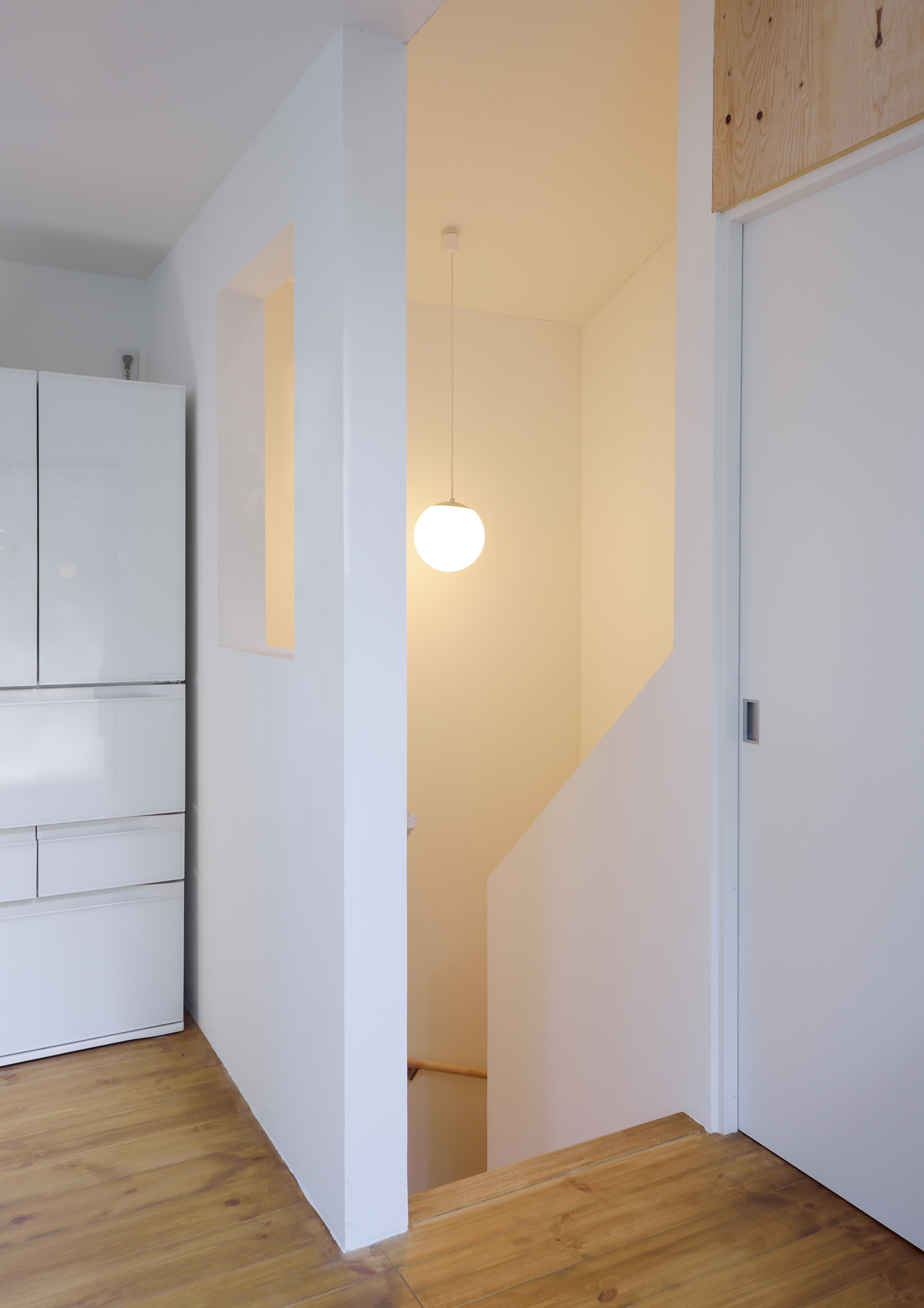 丸い間接照明が取り付けられた白い壁の階段室・デザイン住宅