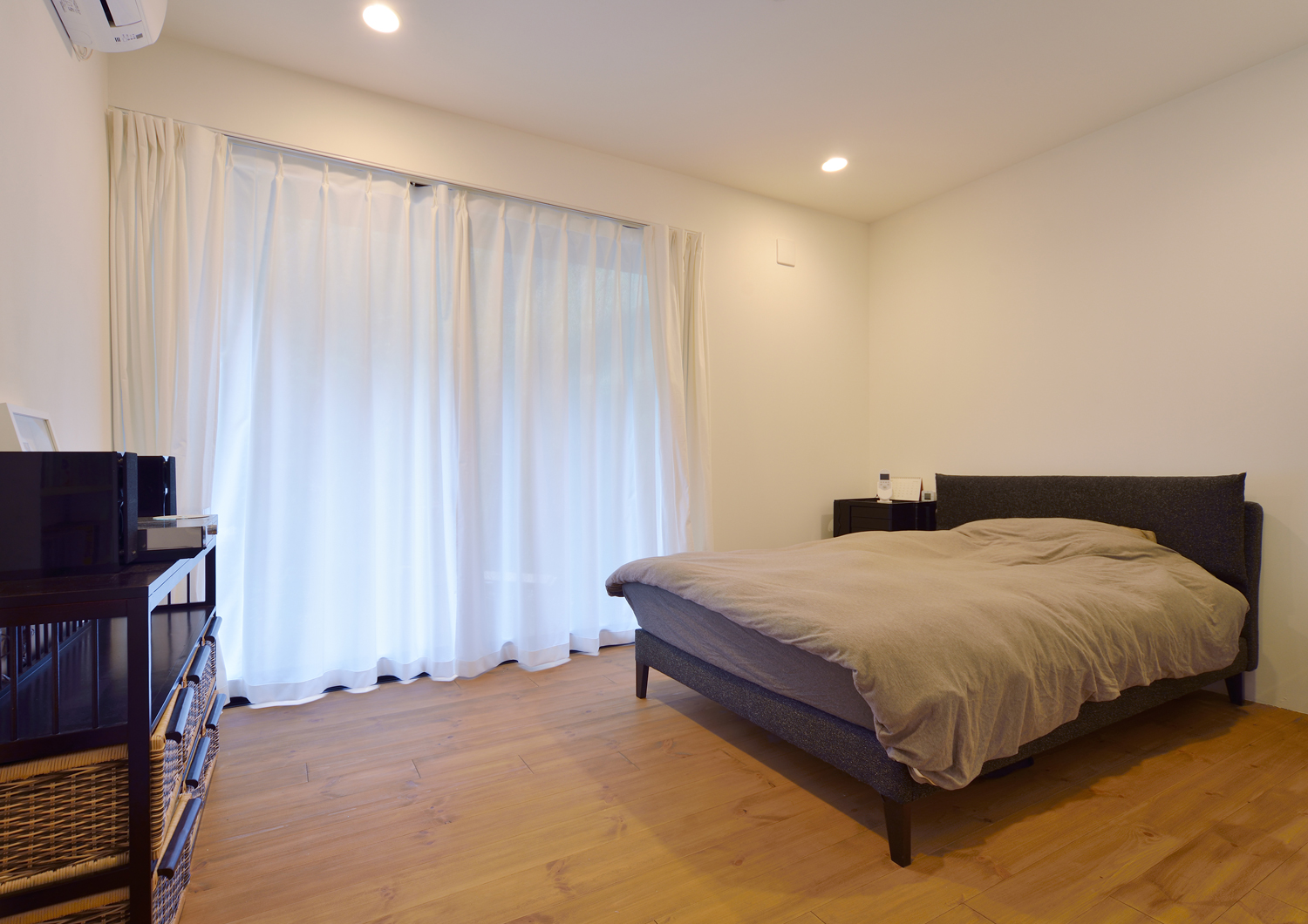 落ち着きのある色のベッドや家具がある窓付きのシンプルな寝室・デザイン住宅