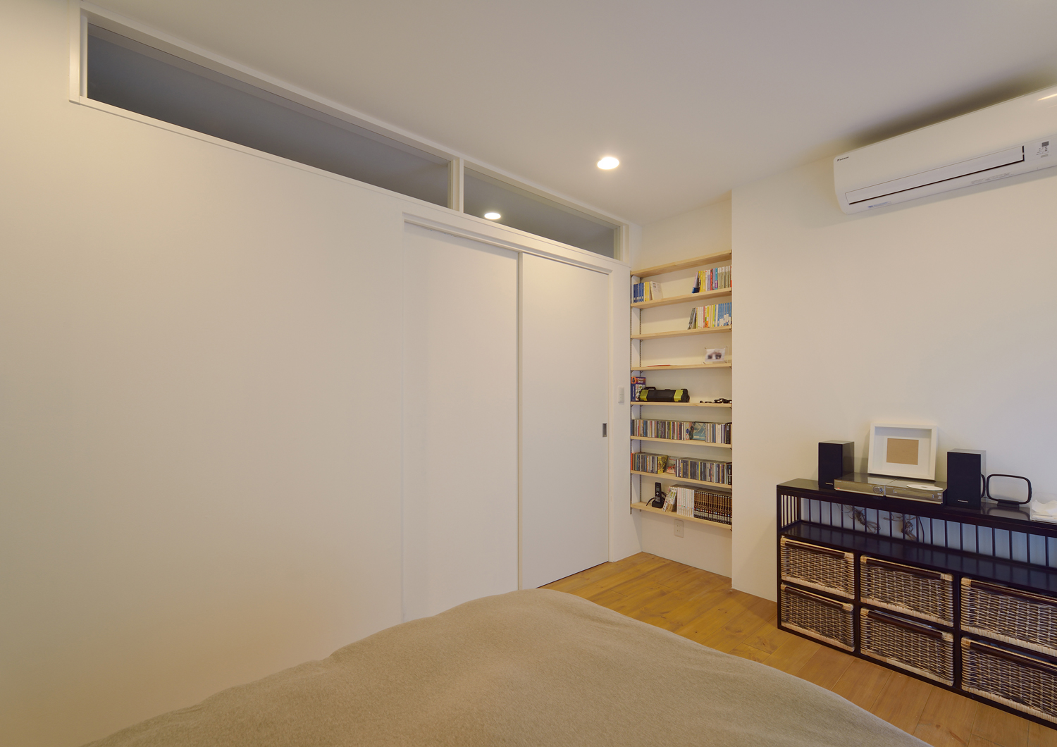 壁付けの本棚がある白い壁のシンプルな寝室・デザイン住宅