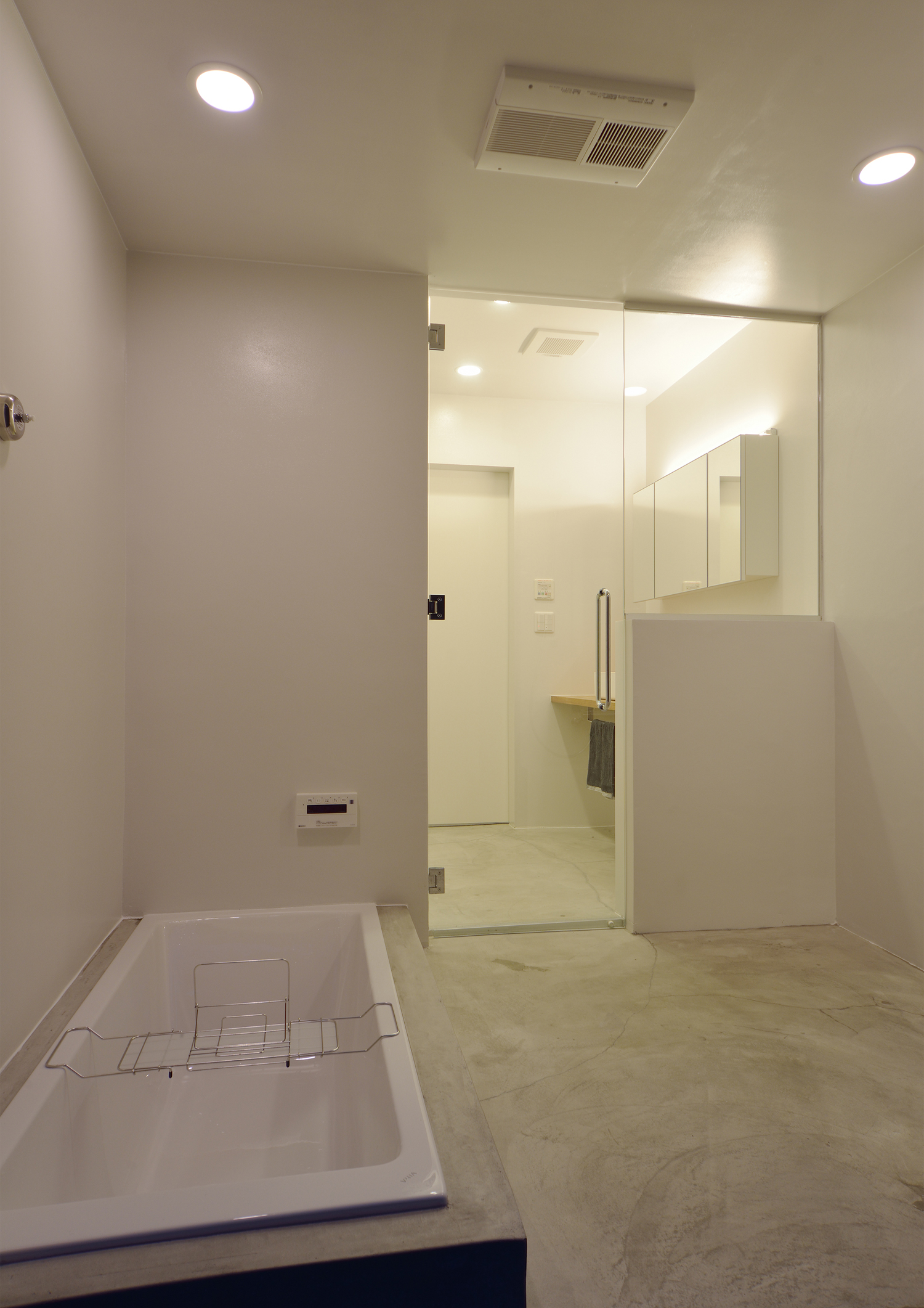 洗面所とガラス扉で繋がるモルタルの在来浴室・デザイン住宅