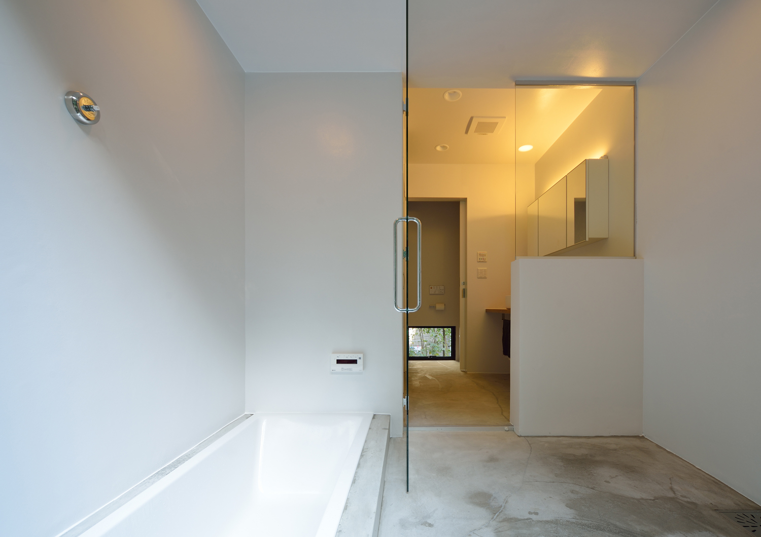 ガラス扉が取り付けられたコンクリートの在来浴室・デザイン住宅