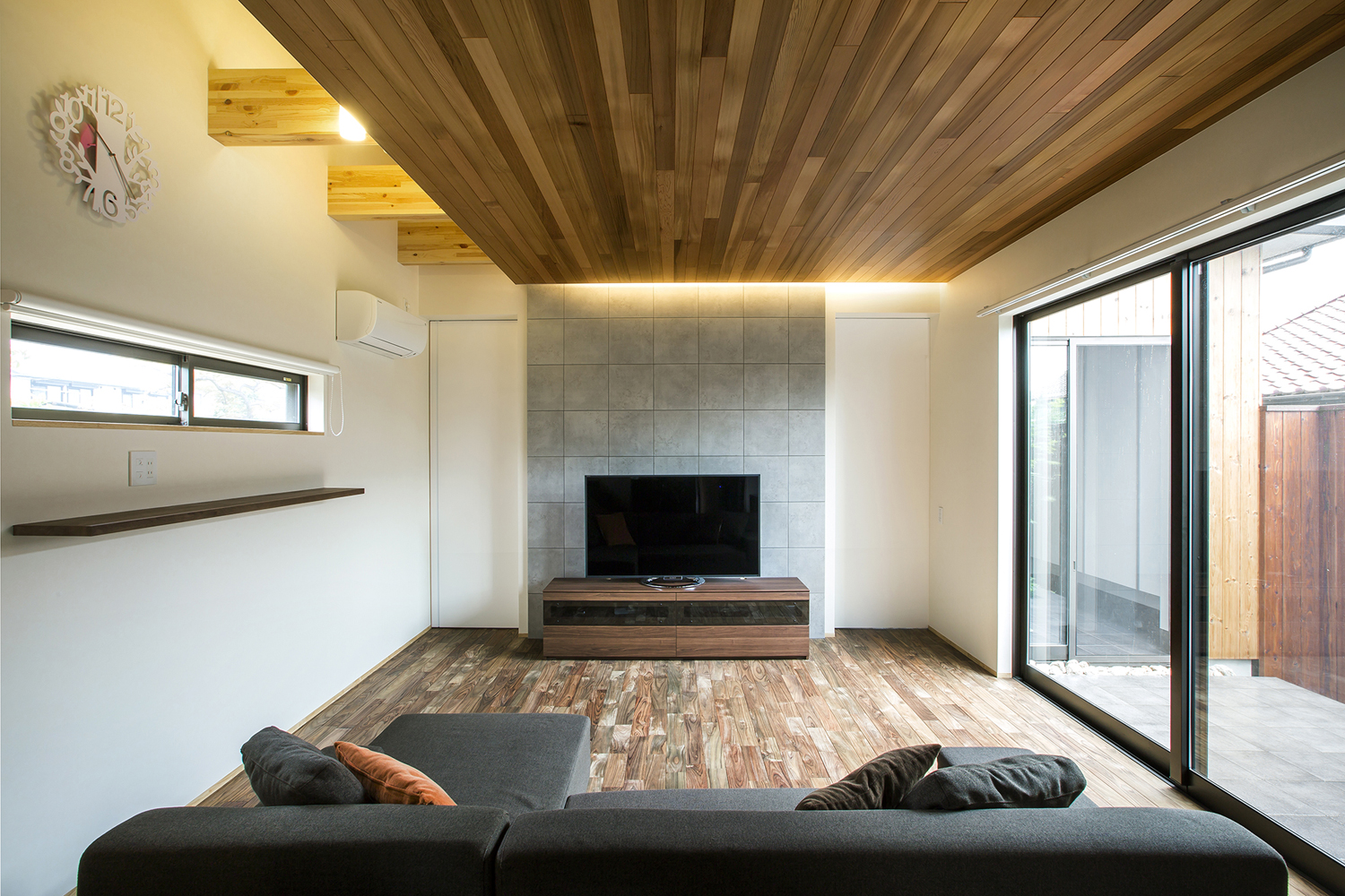 壁際に間接照明が取り付けられた木目の天井のおしゃれなLDK・デザイン住宅