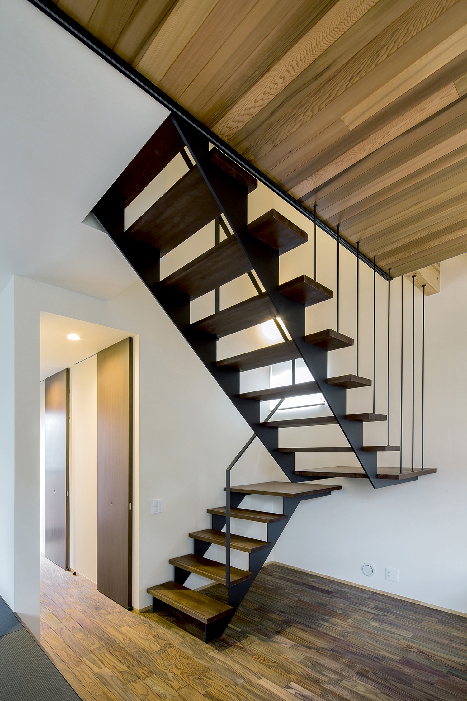 ワイヤーで吊るされたスケルトン階段のある木目の天井のLDK・デザイン住宅