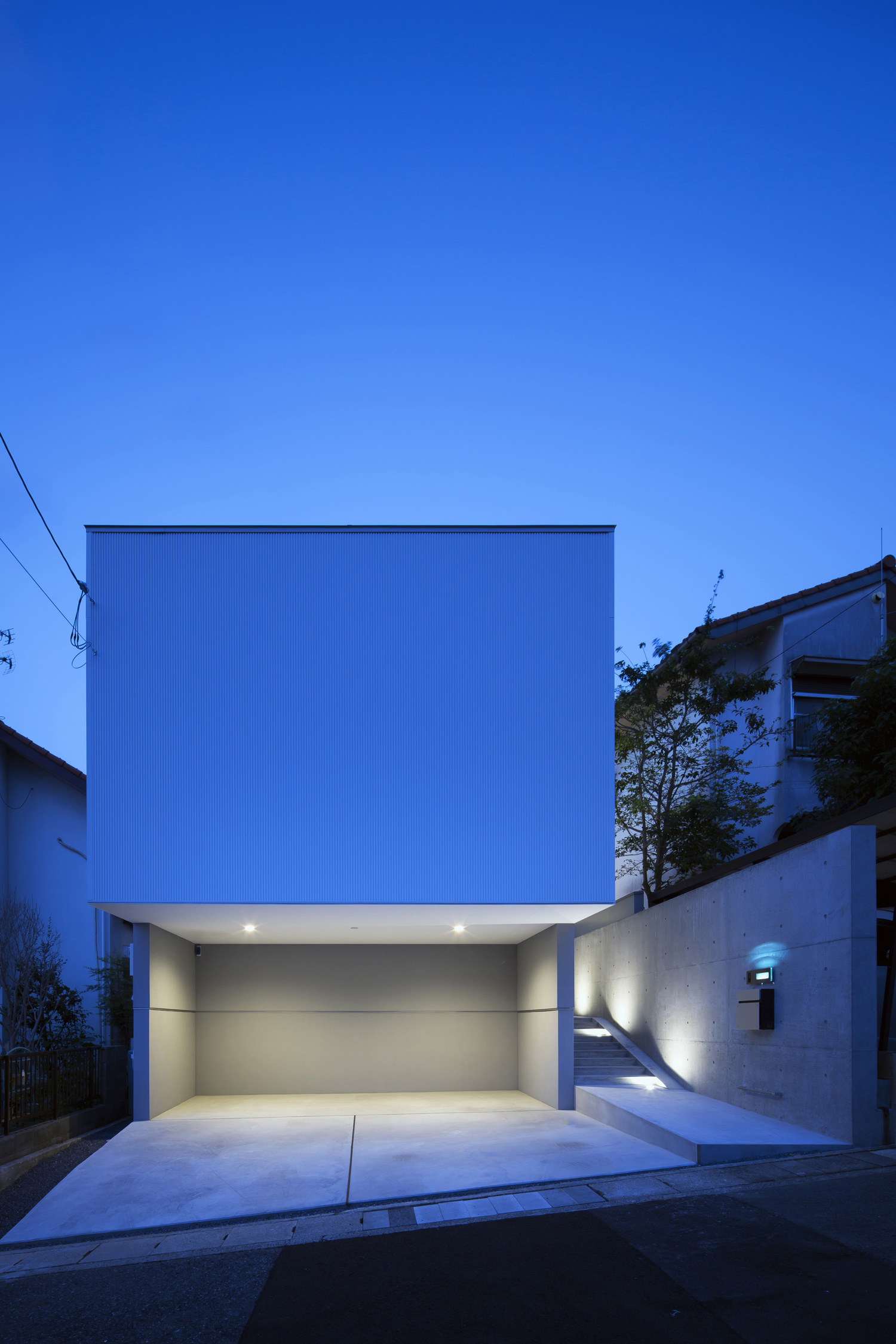 照明付きのインナーガレージがある白いキューブ状の家・デザイン住宅