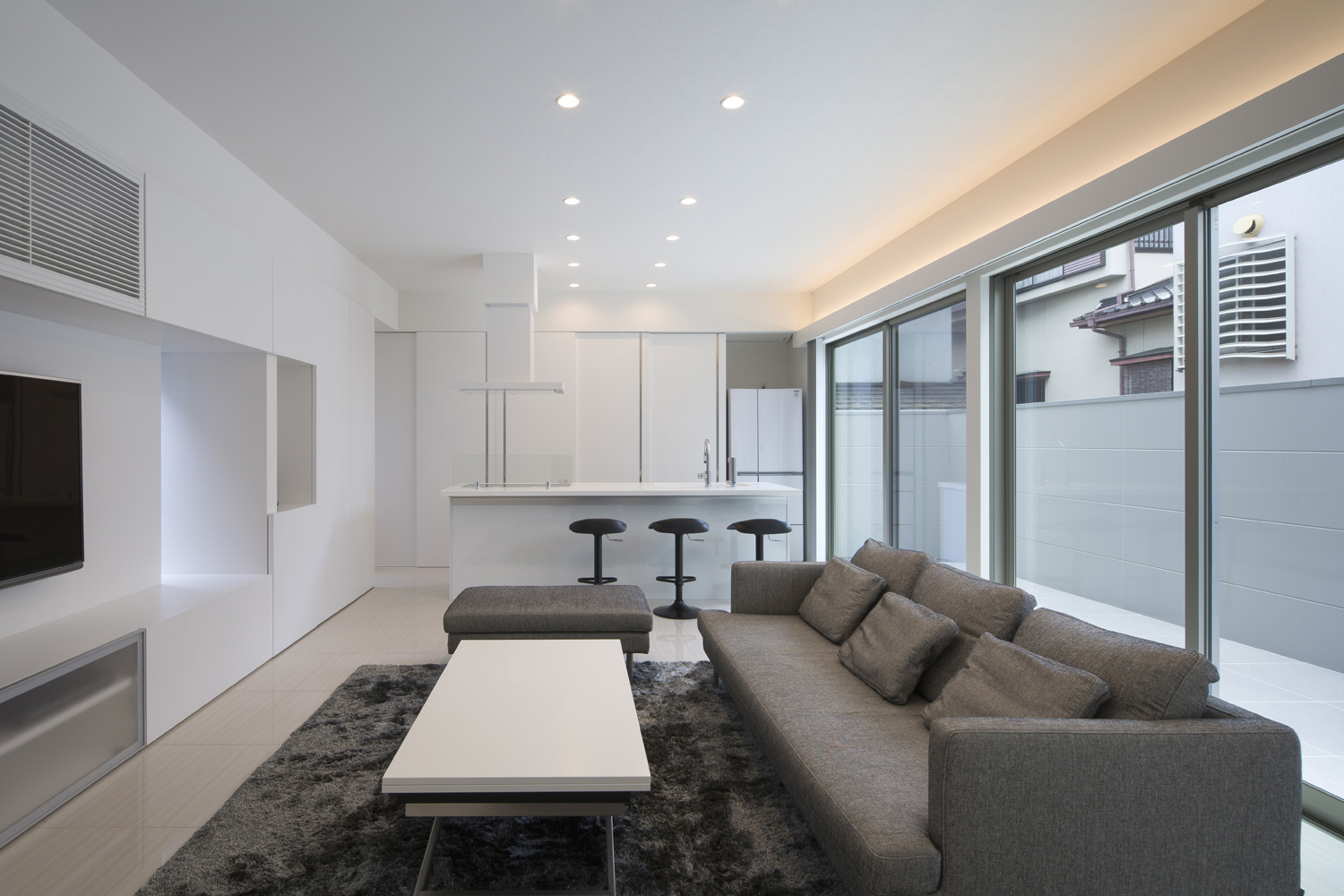 スタイリッシュなグレーのソファと白いコーヒーテーブルのあるモダンなLDK・デザイン住宅