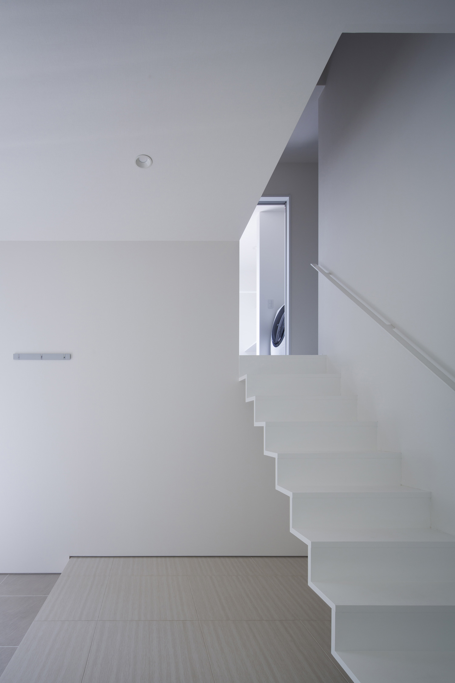 手すり付きの白いスケルトン階段が取り付けられたスキップフロア・デザイン住宅