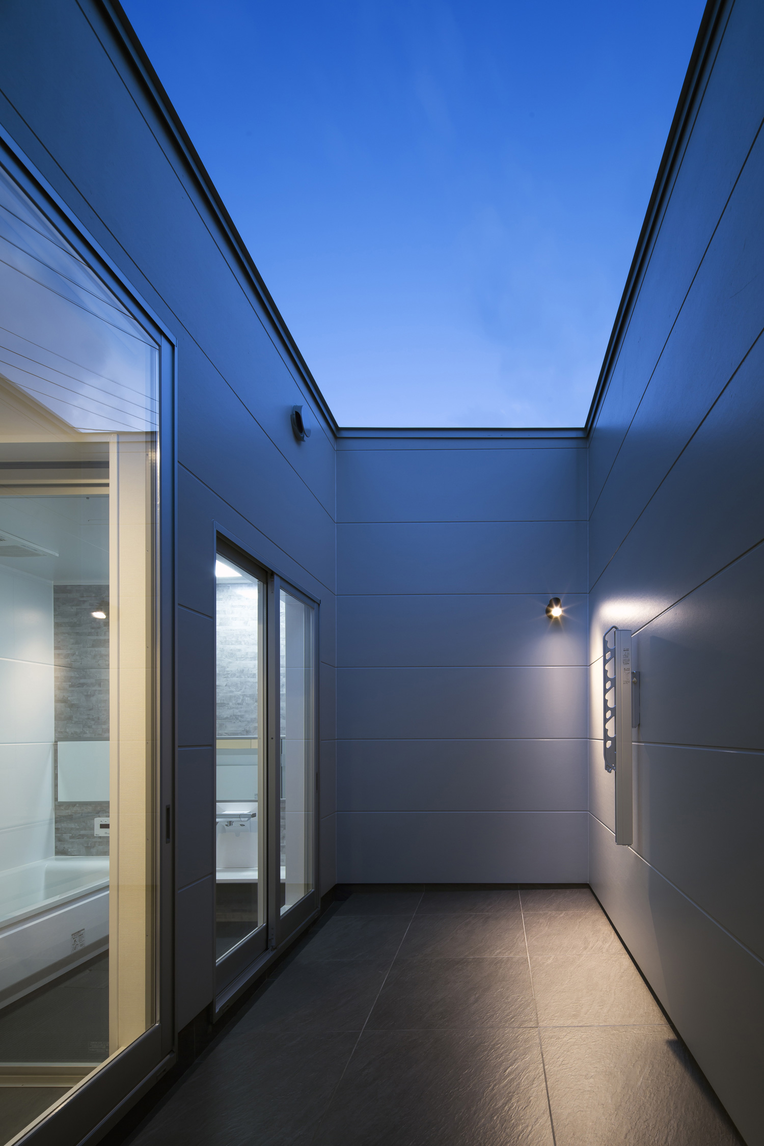 高めの目隠し壁が取り付けられたプライベートなテラス・デザイン住宅