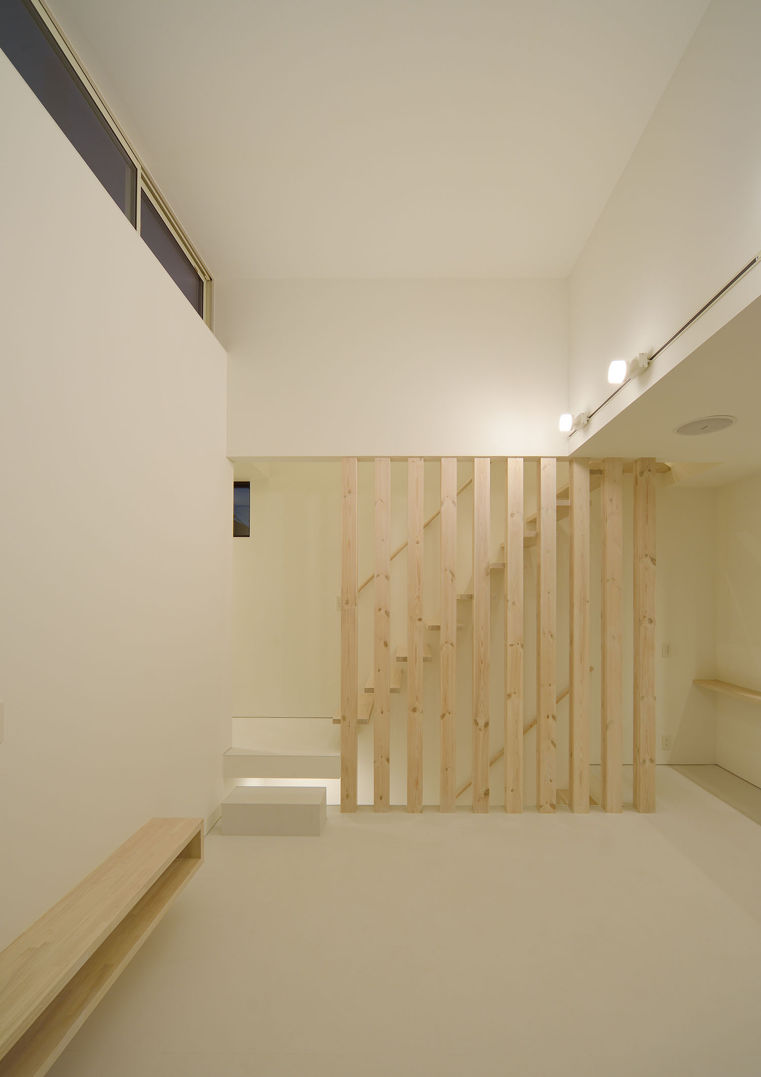 高天井の壁にスポットライトが取り付けられたルーバーの壁があるLDK・デザイン住宅