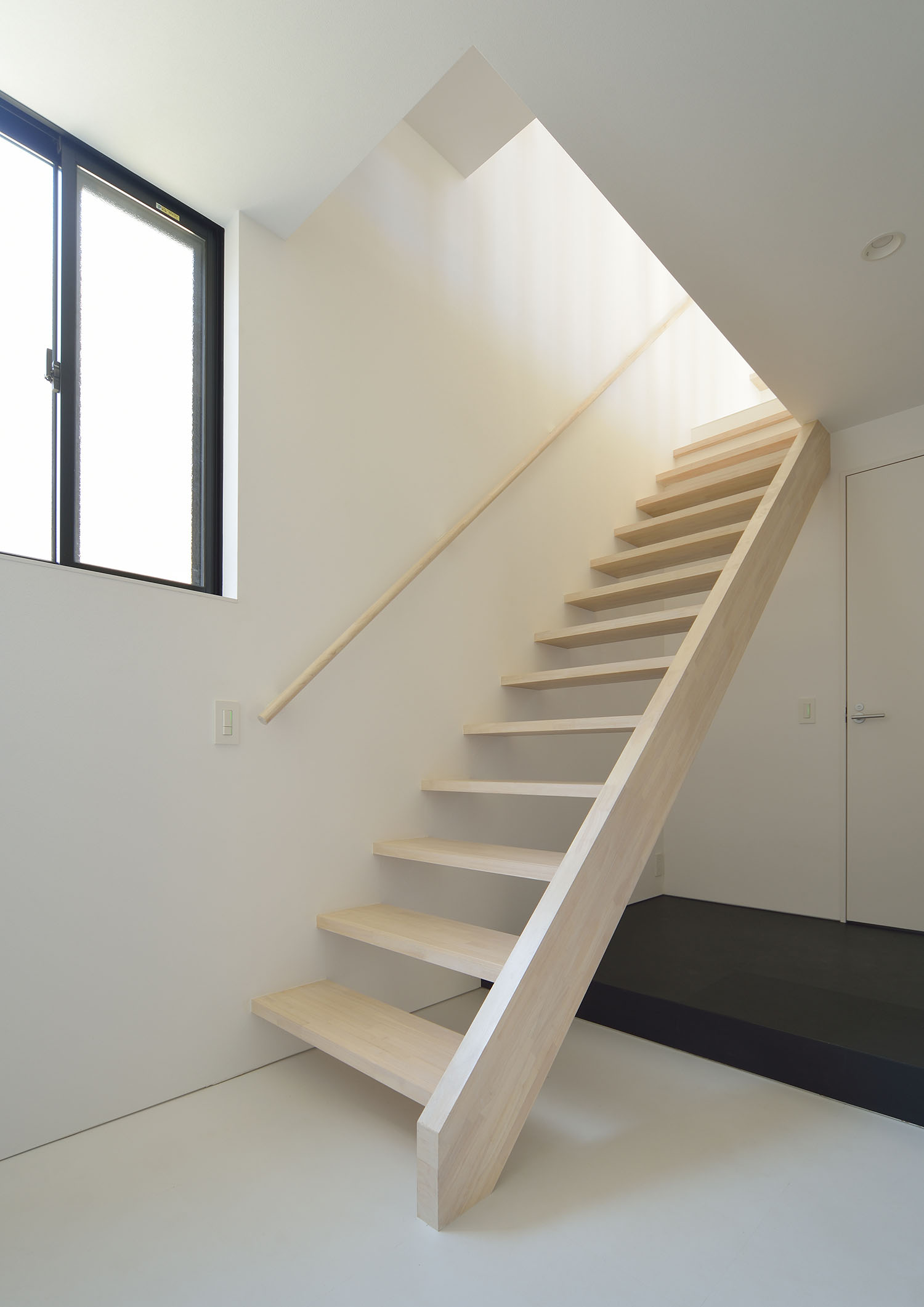 玄関のそばにある薄い色の木材のスケルトン階段・デザイン住宅