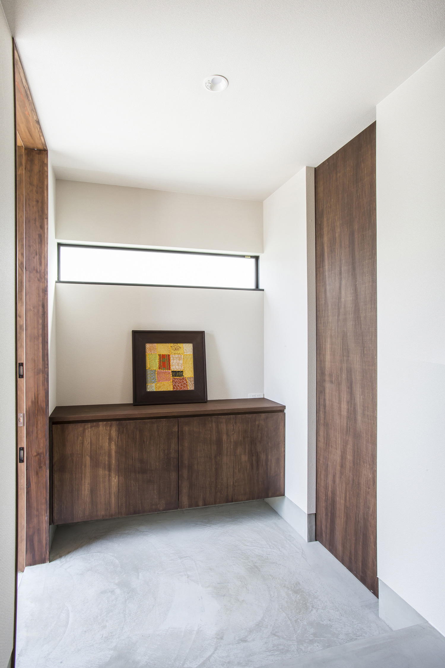 木の引き戸や収納が取り付けられたシンプルな玄関・デザイン住宅