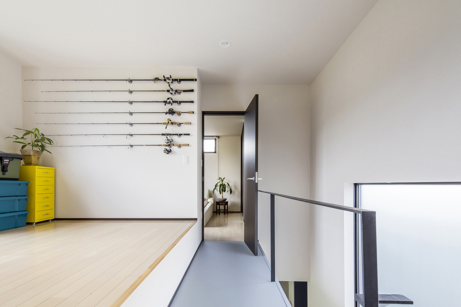 壁に釣り竿が飾られた二階の廊下に面したフリースペース・デザイン住宅