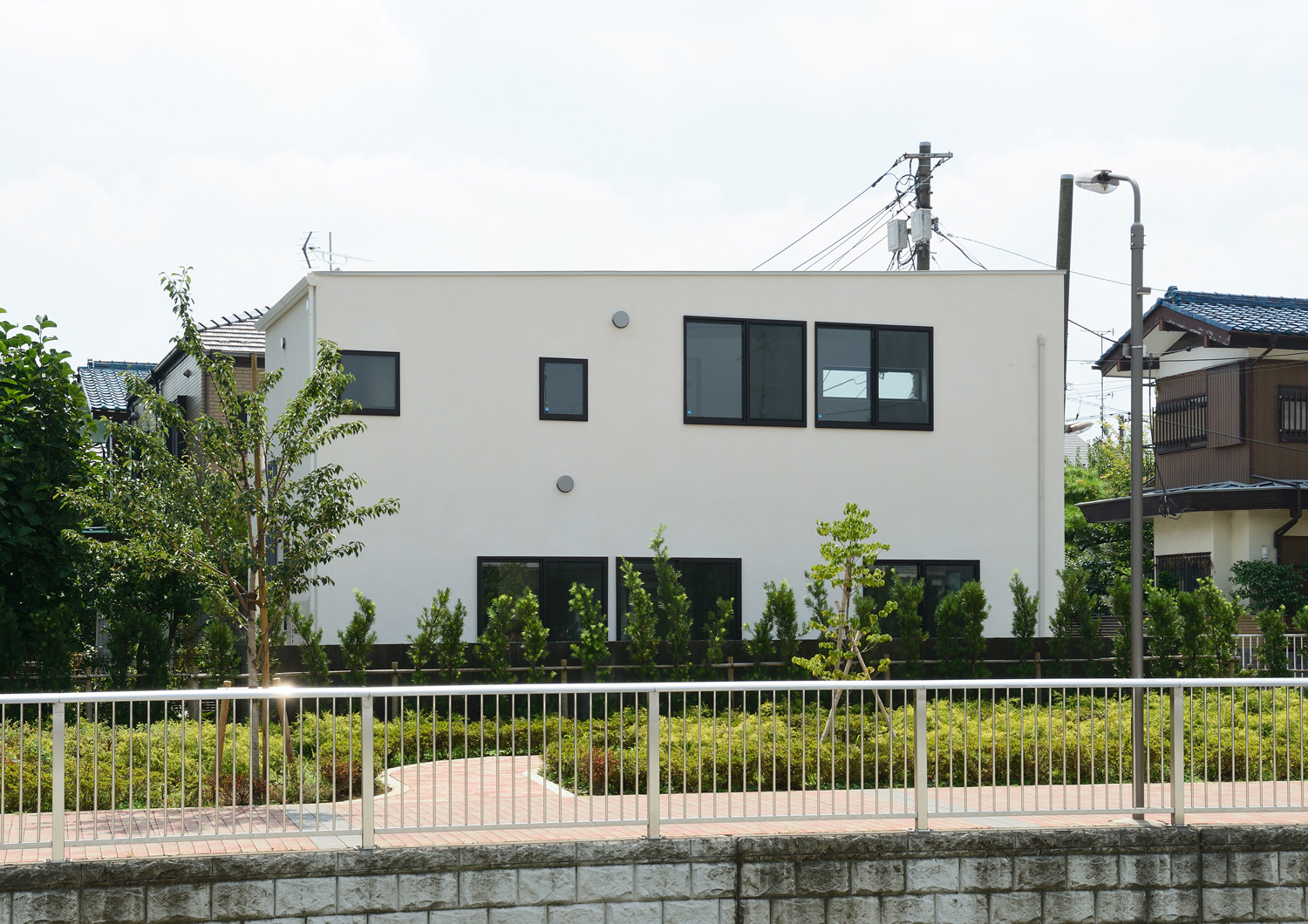 川沿いの住宅街に建つ白いスクエアな外観の家・デザイン住宅