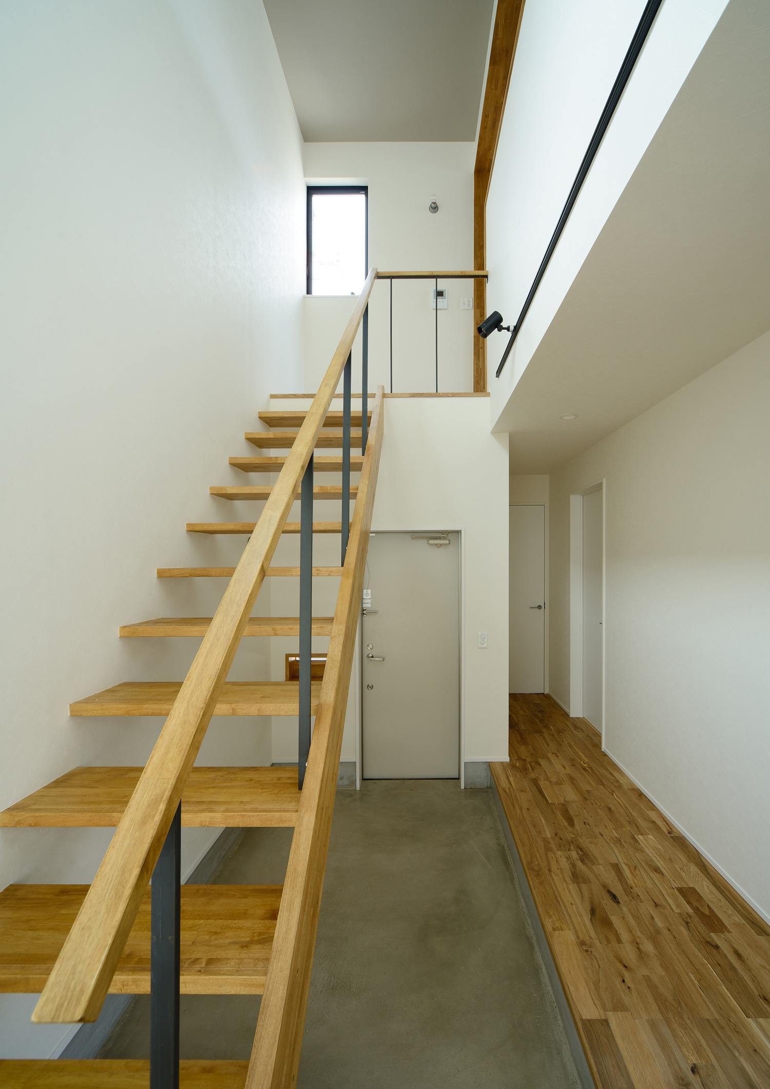 モルタルの土間玄関にある木のスケルトン階段・デザイン住宅