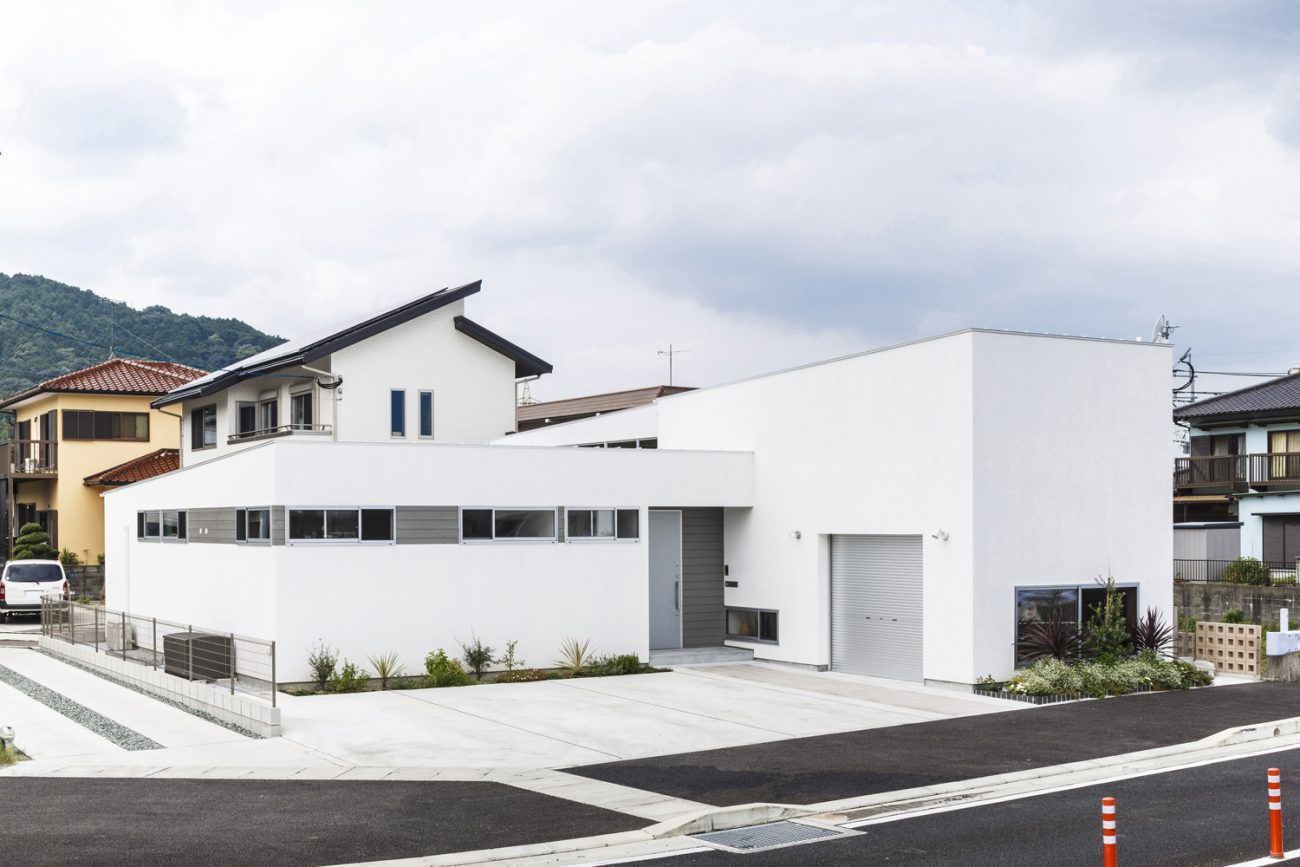 広い道路に面した白いシンプルな外観の家・デザイン住宅