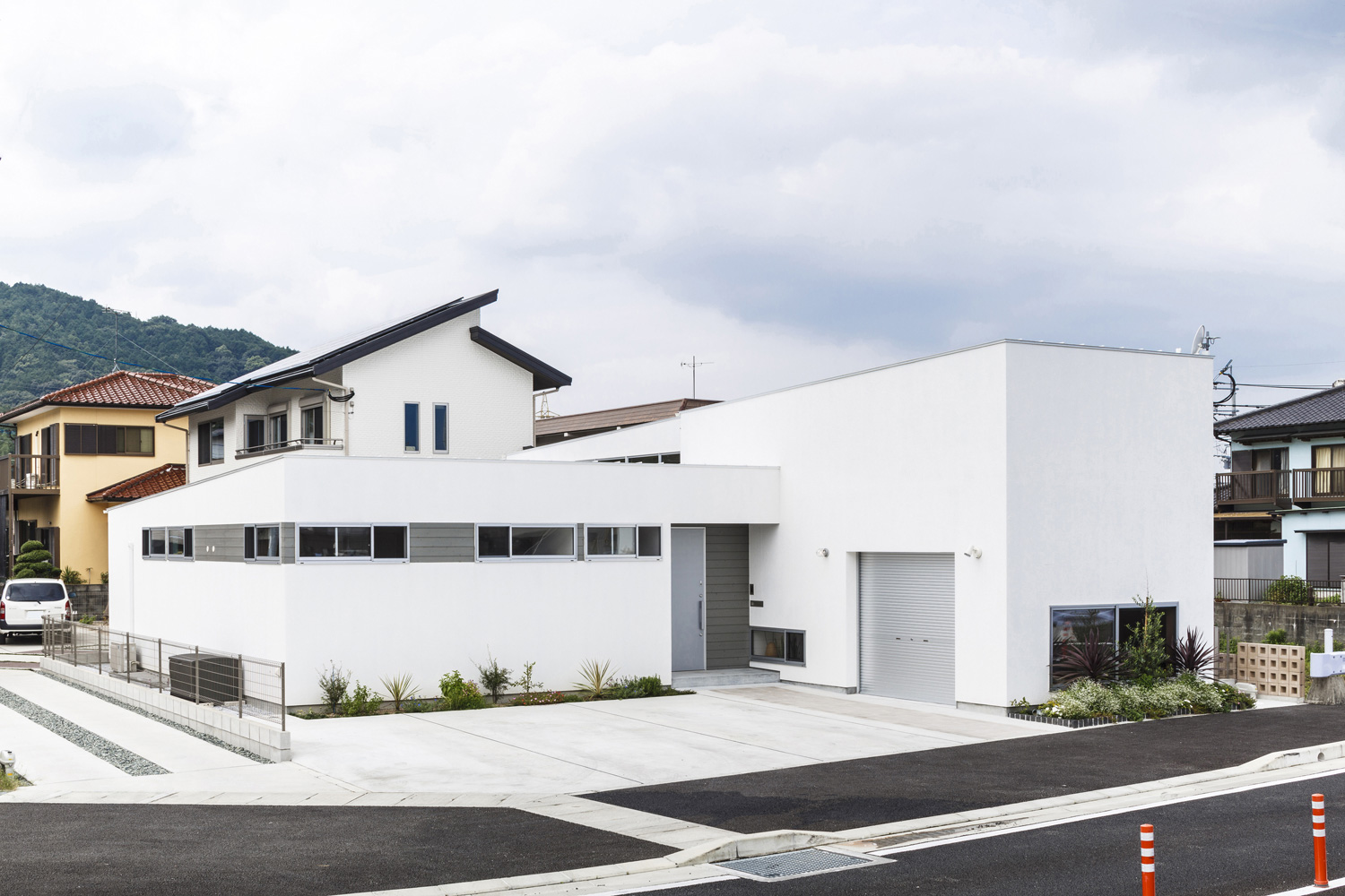 広い道路に面した白いシンプルな外観の家・デザイン住宅