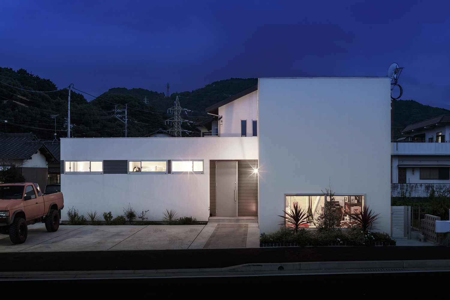 コンクリートの駐車場がある白い外壁のスクエアな家・デザイン住宅