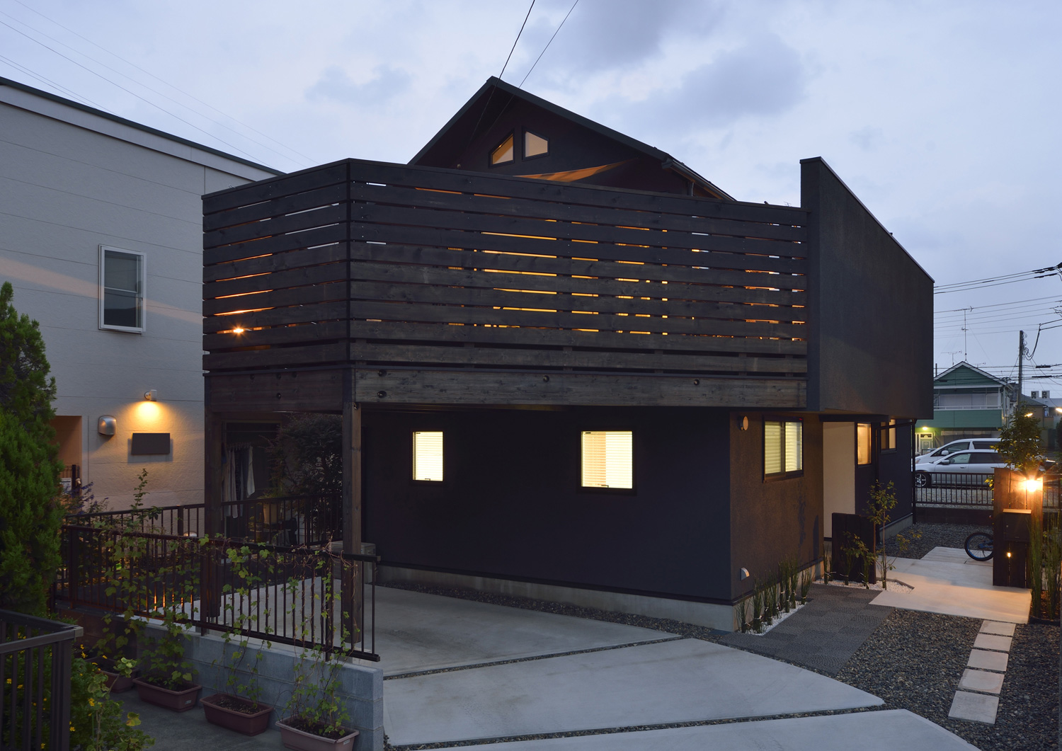 駐車場の上に木の目隠し付きのバルコニーがあるシンプルでおしゃれな外観の家・デザイン住宅