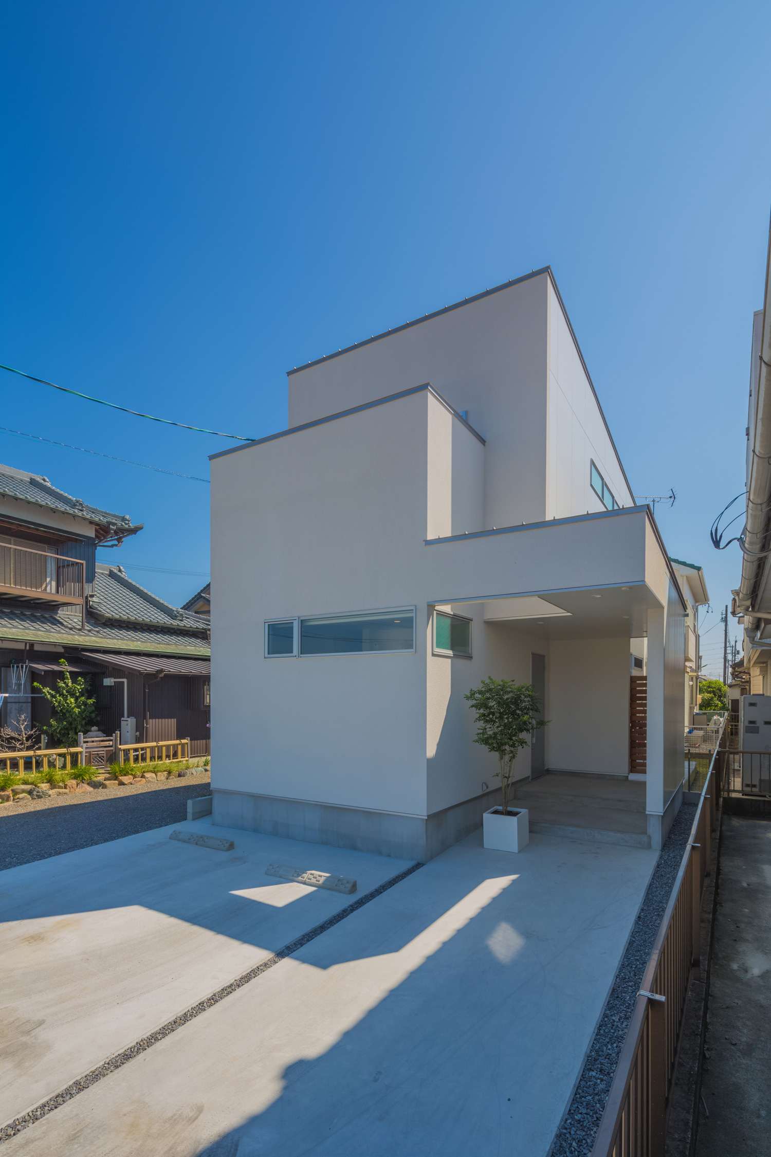 広い駐車スペースがある白いシンプルなスクエアの外観の家・デザイン住宅