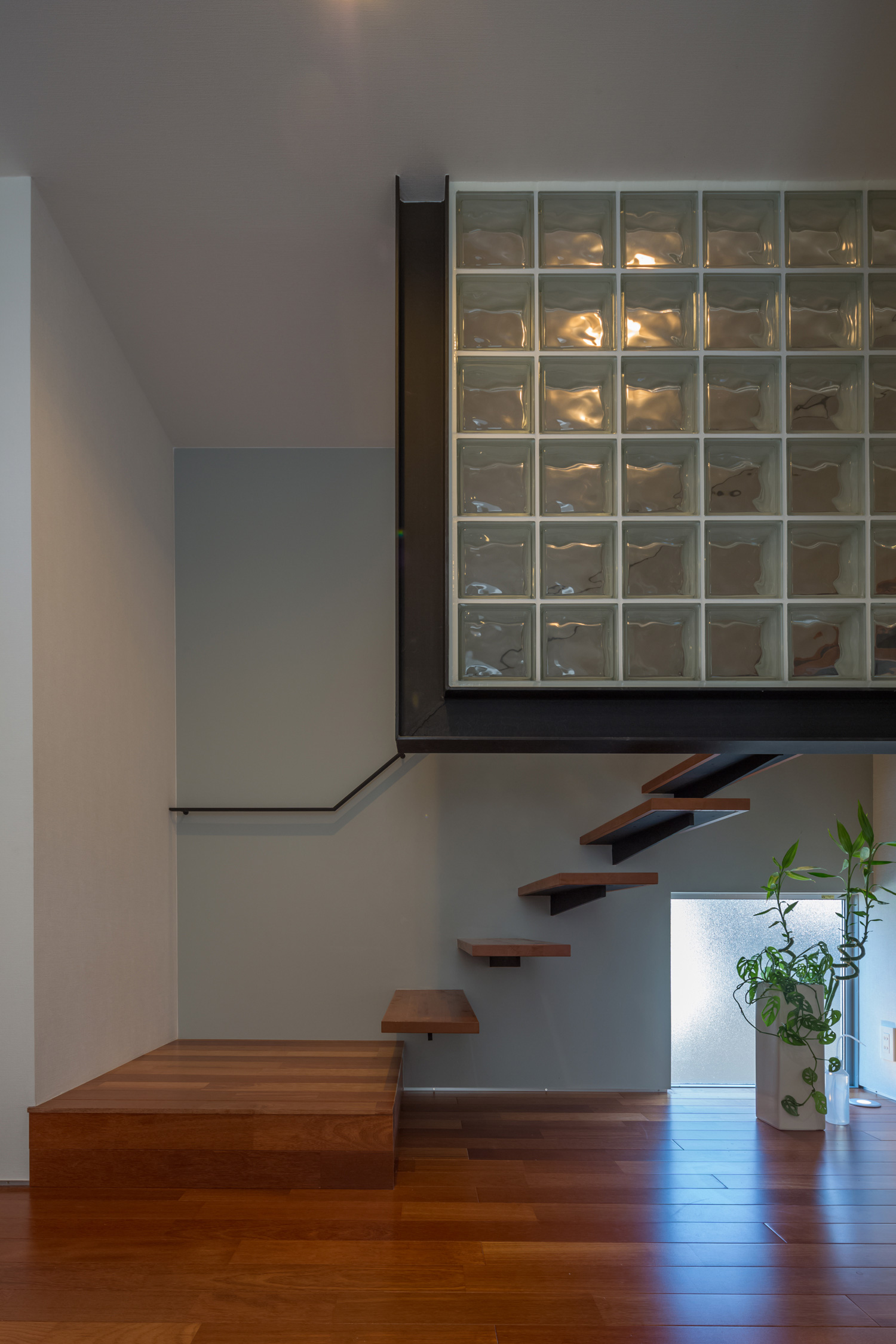 壁にガラスを取り入れた、浮いたデザインの木の階段・デザイン住宅