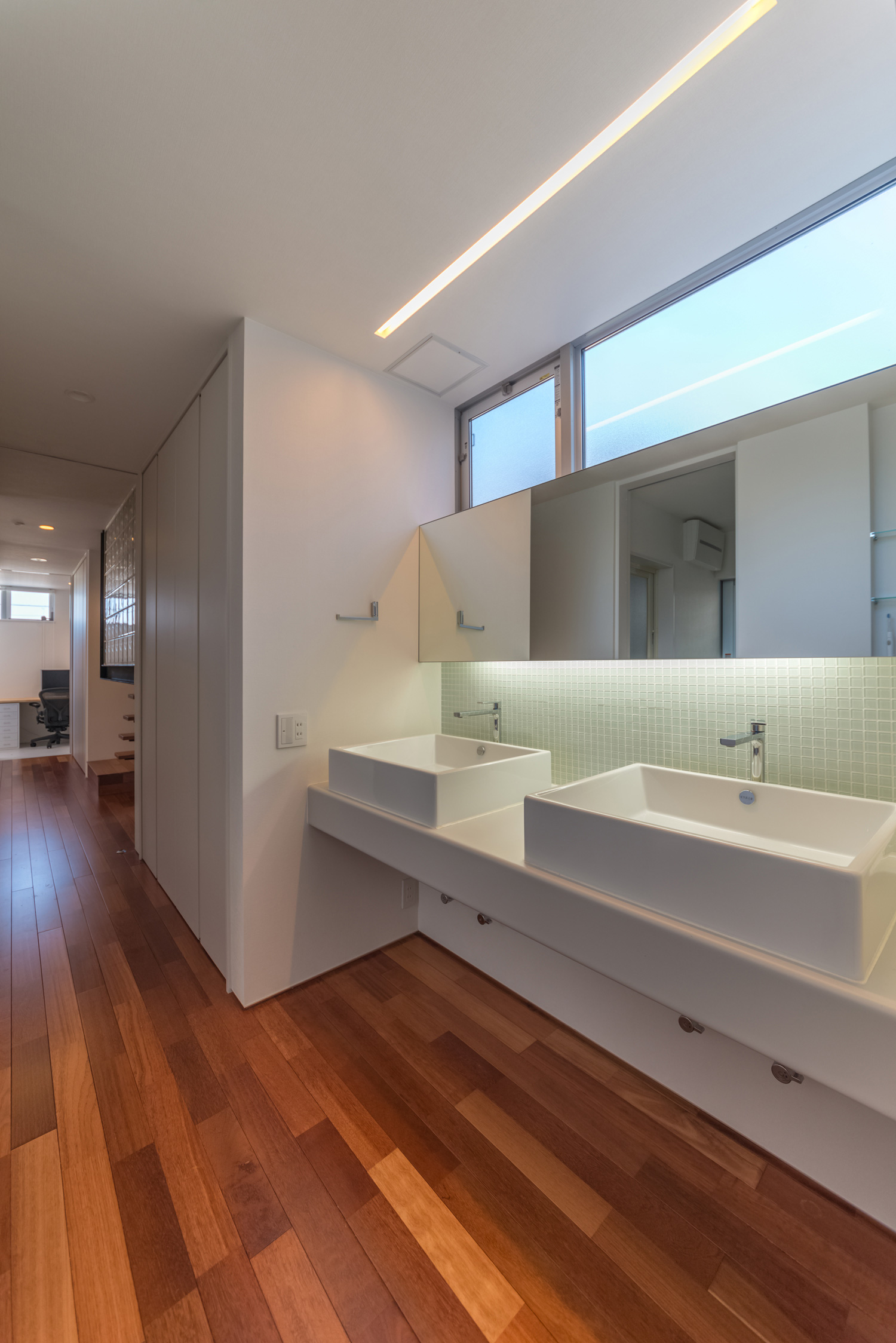 天井にライン状の照明を取り付けたダブルボウルのすっきりとした洗面所・デザイン住宅