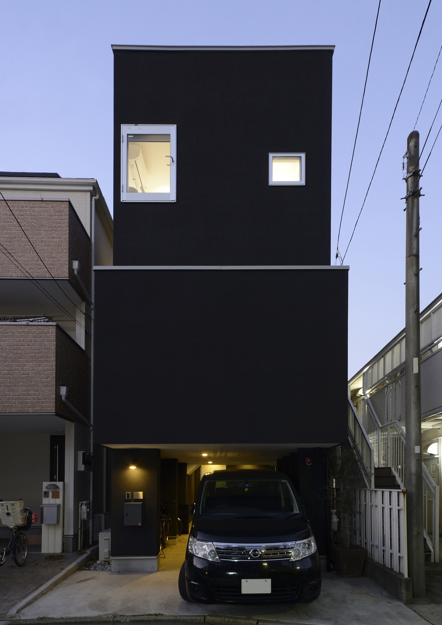 インナーガレージ付きのシンプルな黒い外壁の三階建て住宅・デザイン住宅