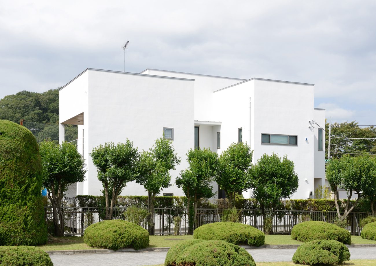 木に囲まれた白い外壁でキューブ状の家・デザイン住宅