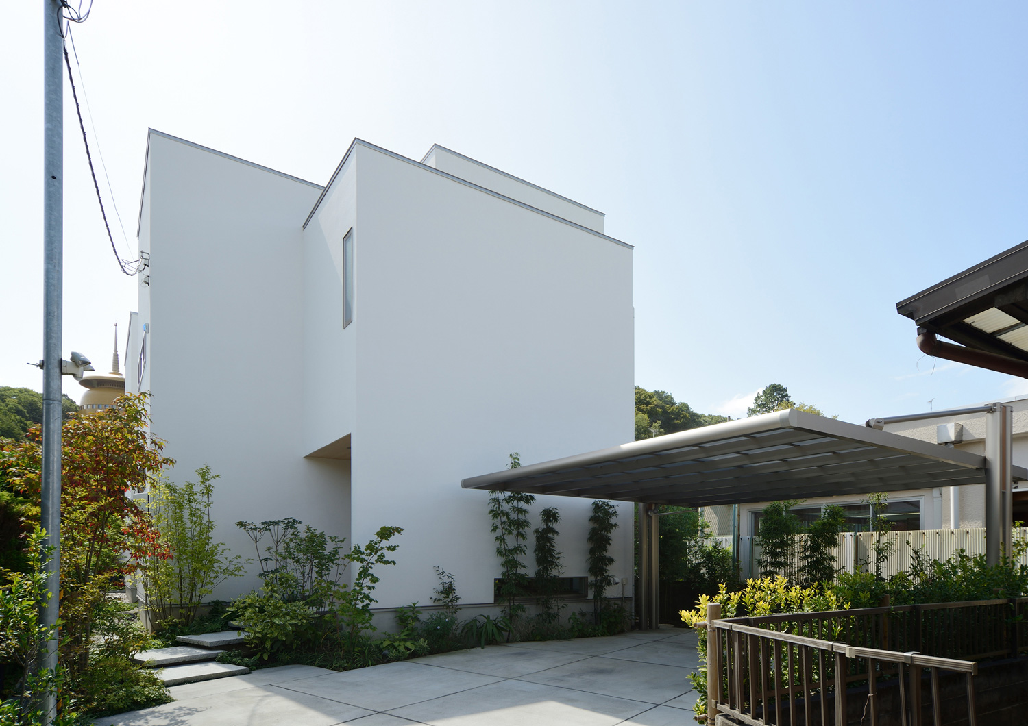 屋根付きのカーポートがある白い窓のない外観の家・デザイン住宅