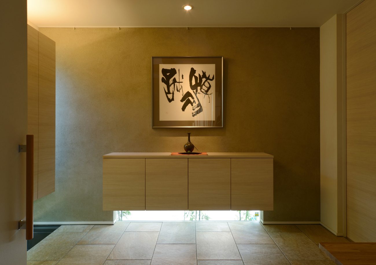 浮いたデザインの収納の下に地窓を取り付けたモダンで和風玄関・デザイン住宅