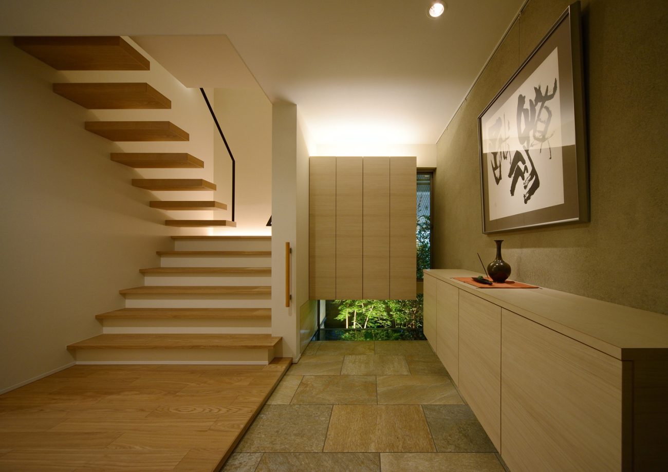 窓からライトアップされた植栽がある広くておしゃれな玄関・デザイン住宅