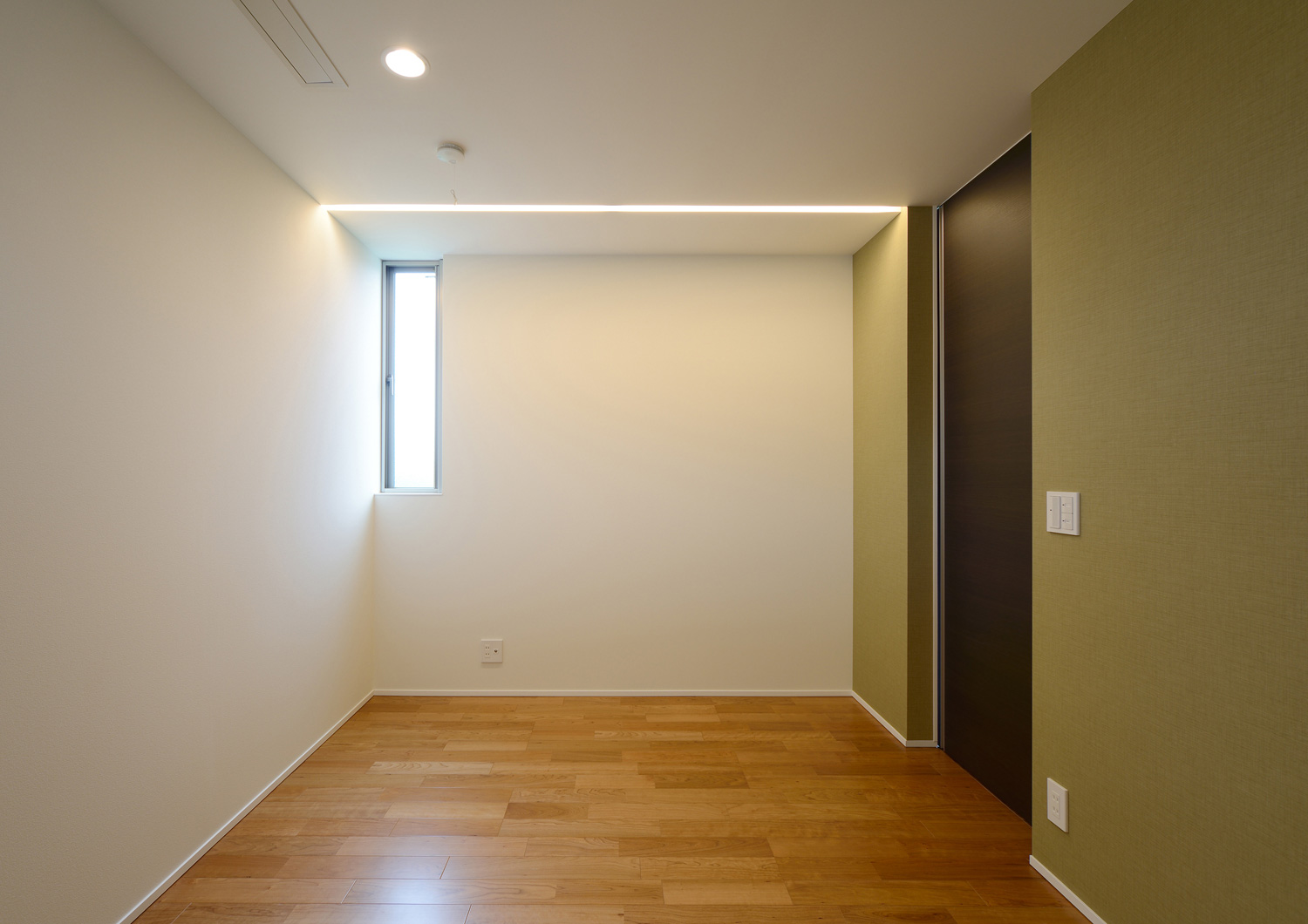 縦長のスリット窓を取り付けたシンプルな寝室・デザイン住宅