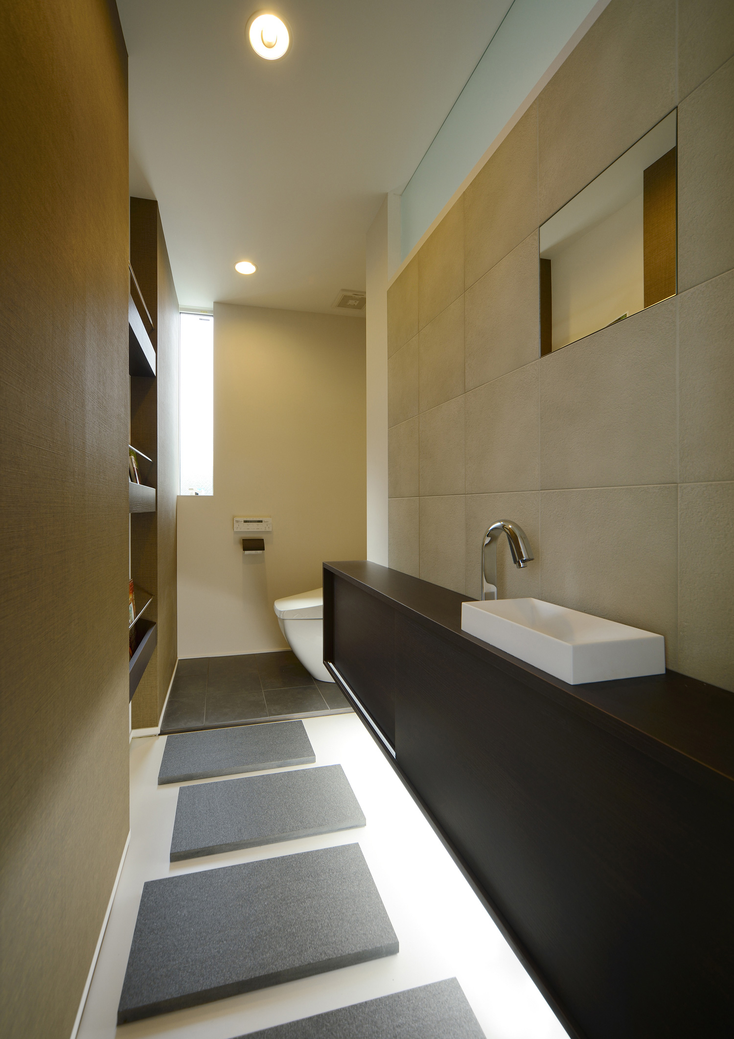 シンプルな手洗いカウンターの下に間接照明を取り付けた広くておしゃれなトイレ・デザイン住宅