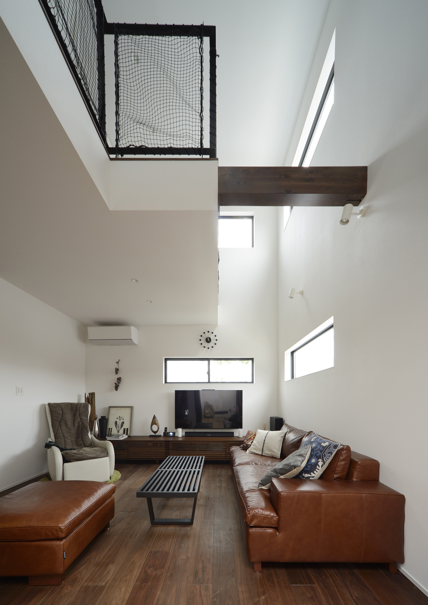 吹き抜けがある濃い色のフローリングの落ち着きのあるLDK・デザイン住宅