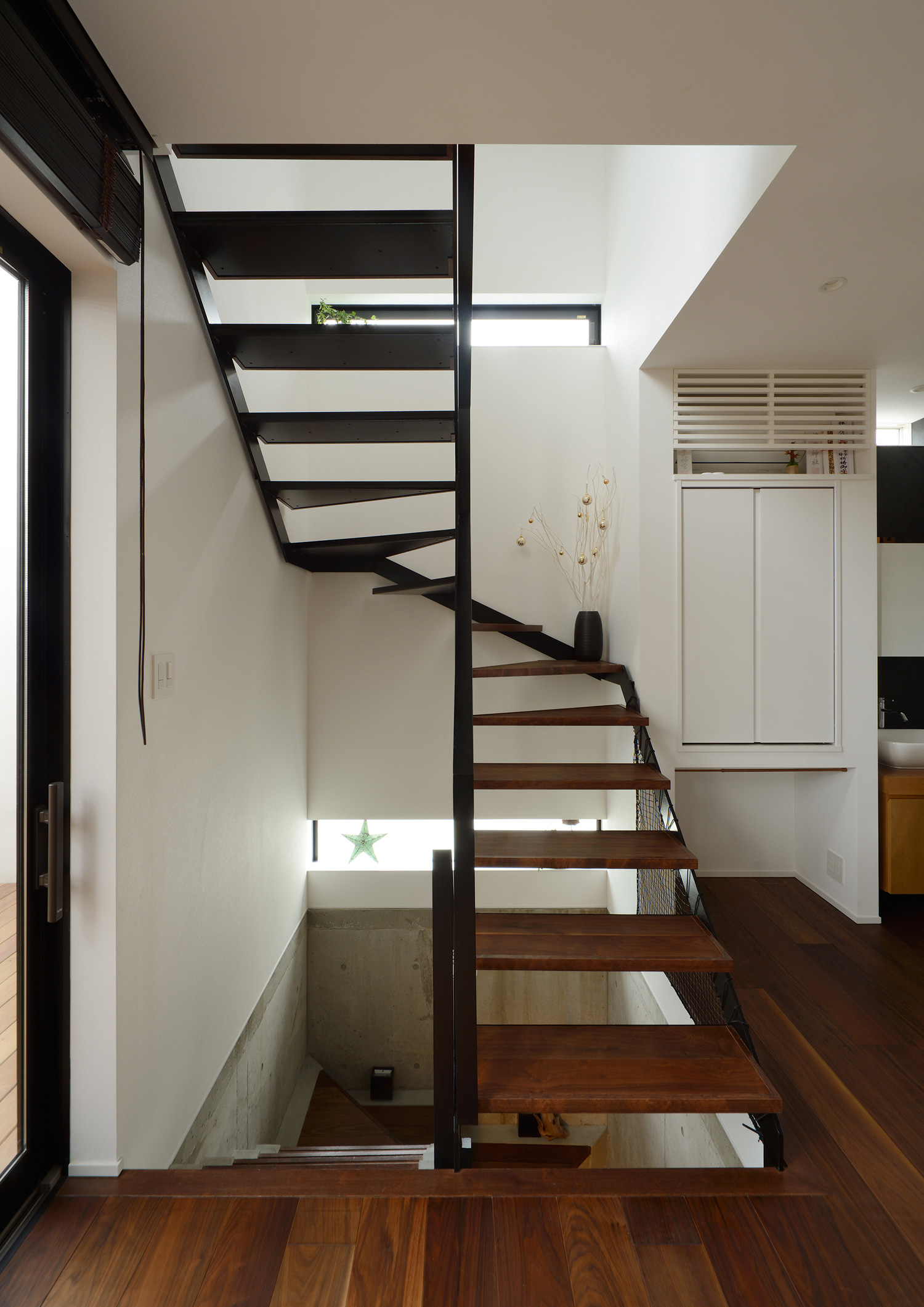 LDKと繋がる黒いアイアンの手すり付きのらせん状のスケルトン階段・デザイン住宅