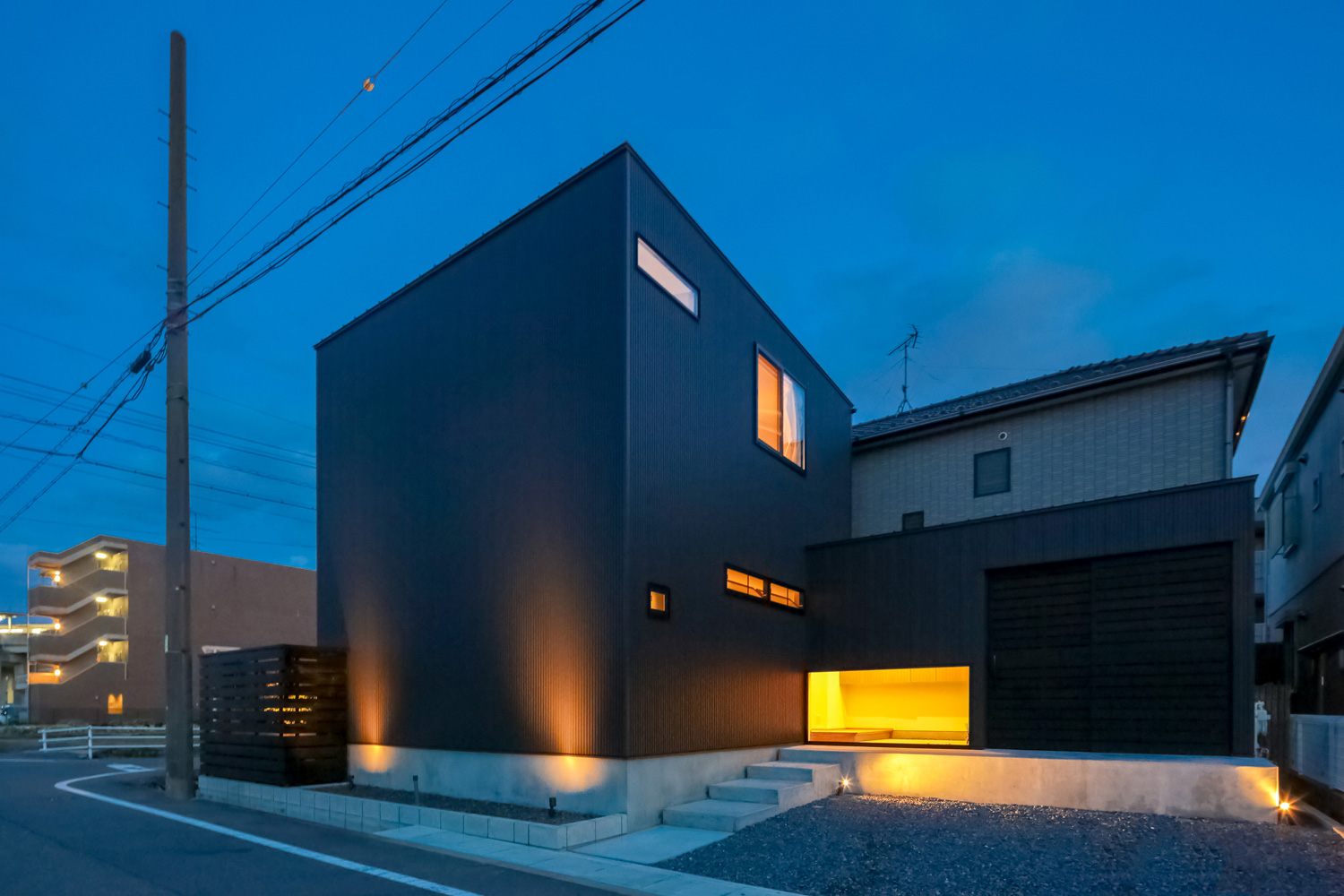 黒い外壁が間接照明に照らされたシンプルでおしゃれな外観の家・デザイン住宅