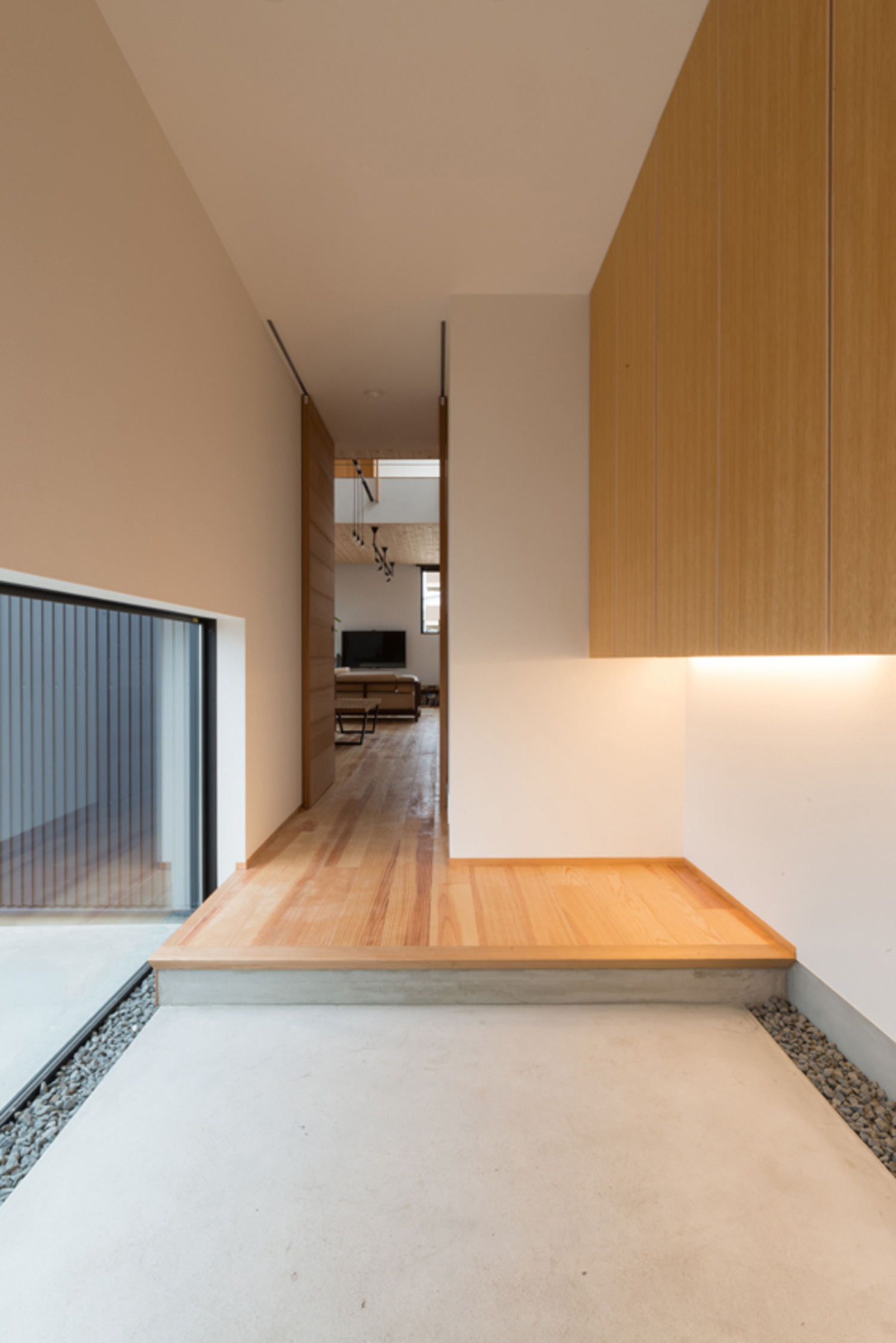 大き目の地窓から光が入るすっきりとしたモルタルの玄関・デザイン住宅