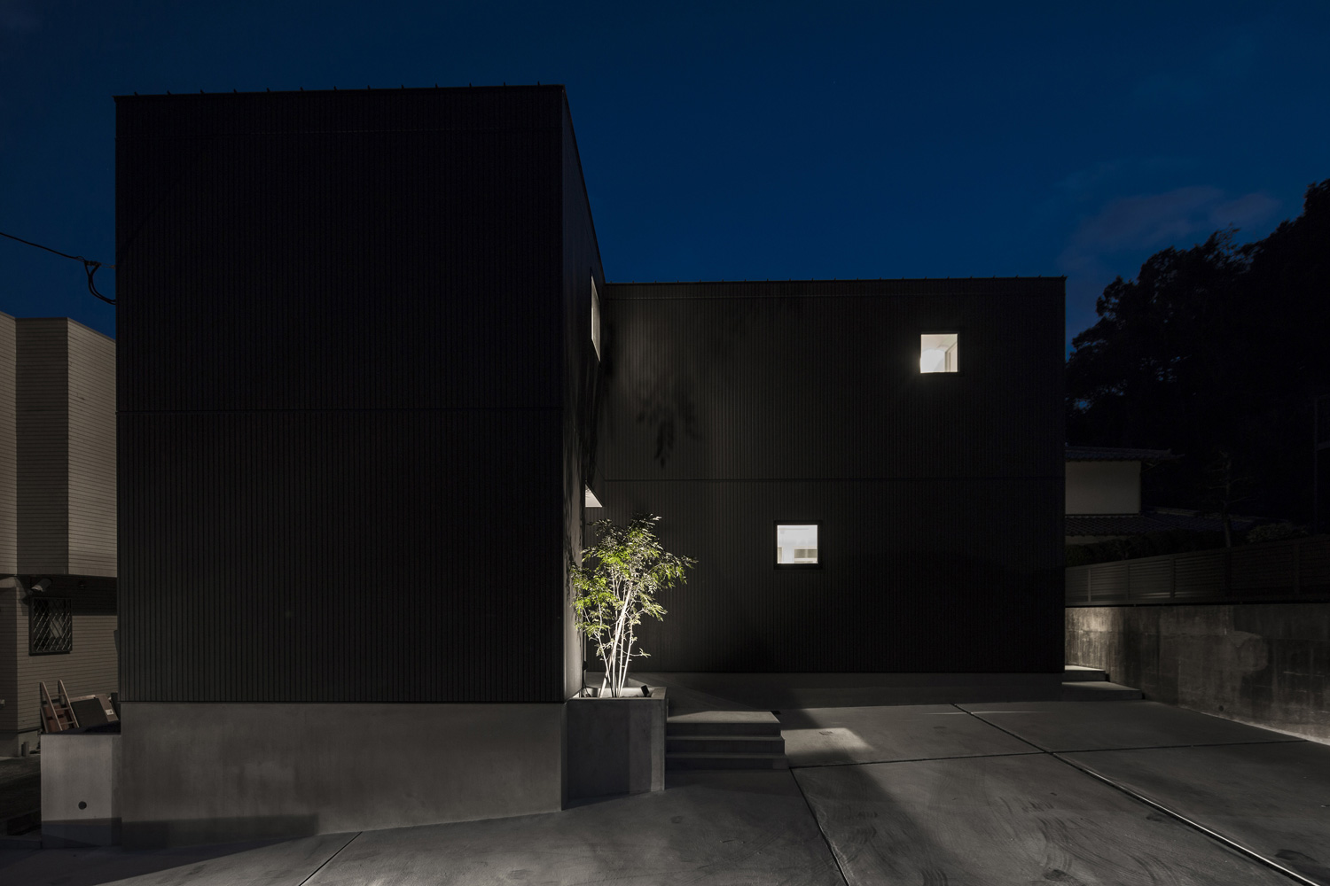 植栽がライトアップされた黒いシンプルな外観の家・デザイン住宅