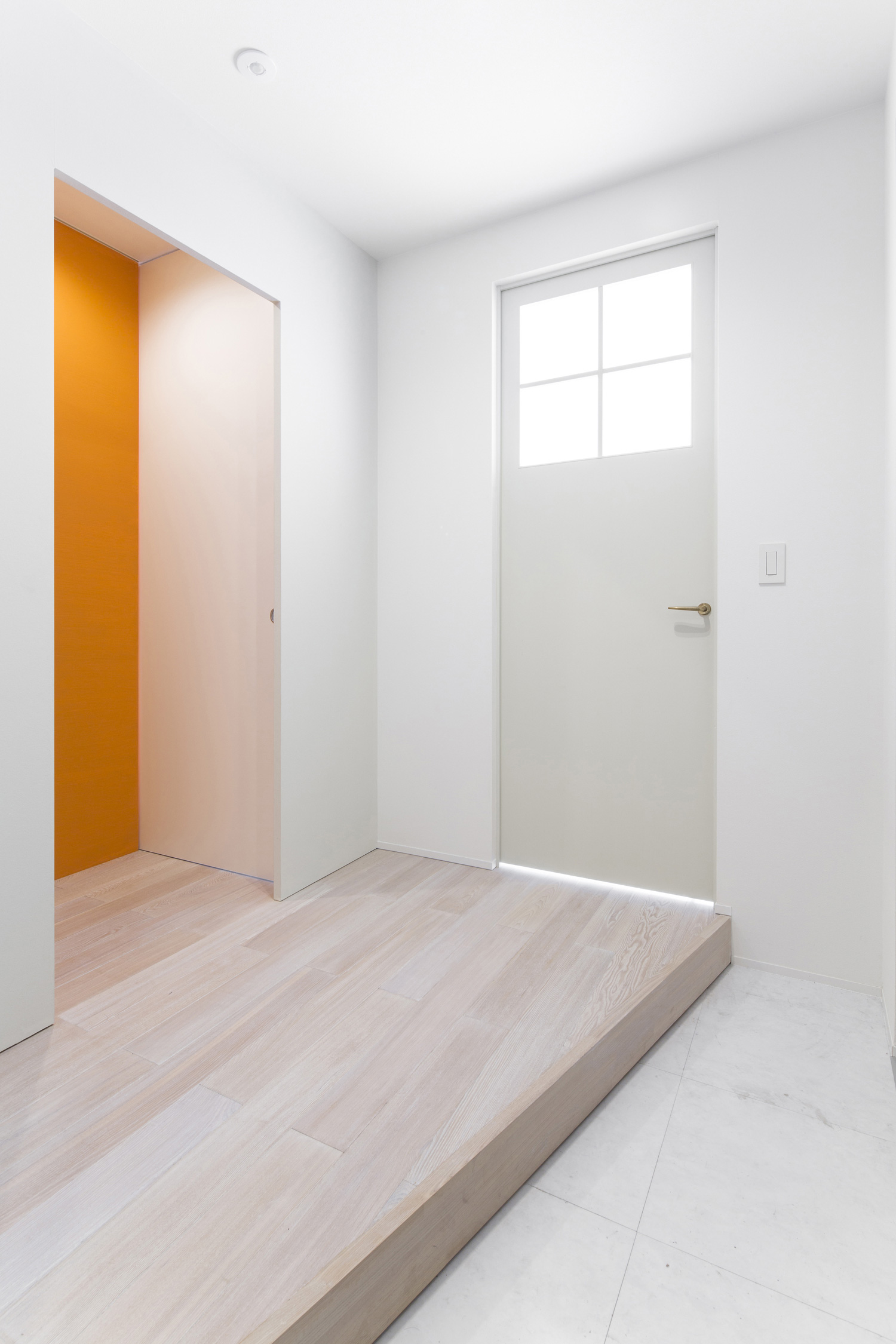 格子窓付きの白い扉が取り付けられたシンプルな玄関・デザイン住宅