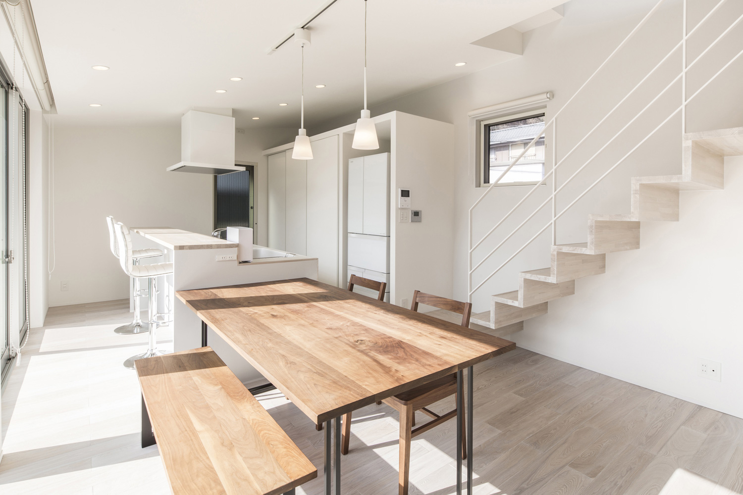 白いキッチンと木のダイニングテーブルが横並びになったおしゃれなLDK・デザイン住宅