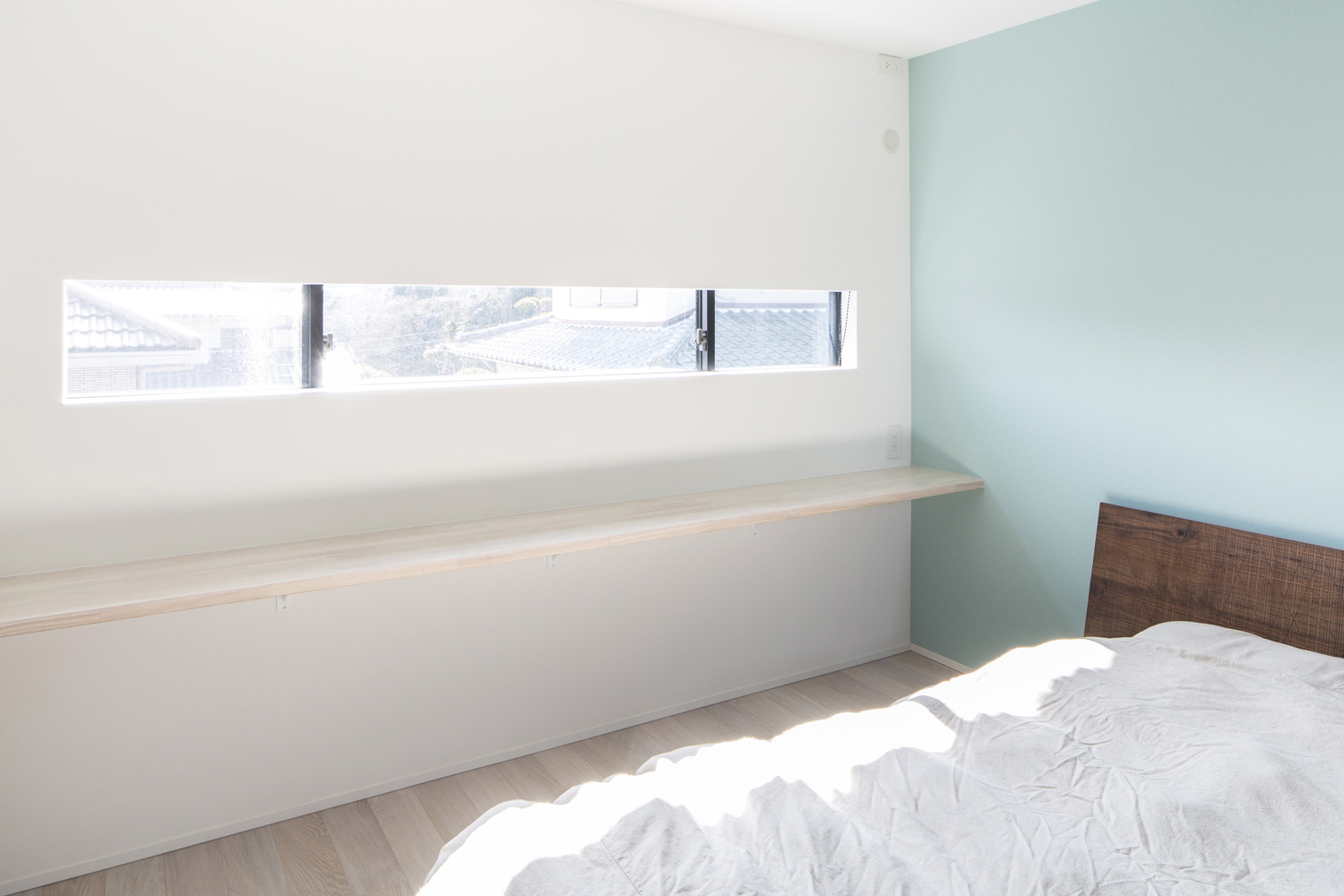 スリット窓と壁付けデスクとアクセントクロスがあるシンプルでおしゃれな寝室・デザイン住宅