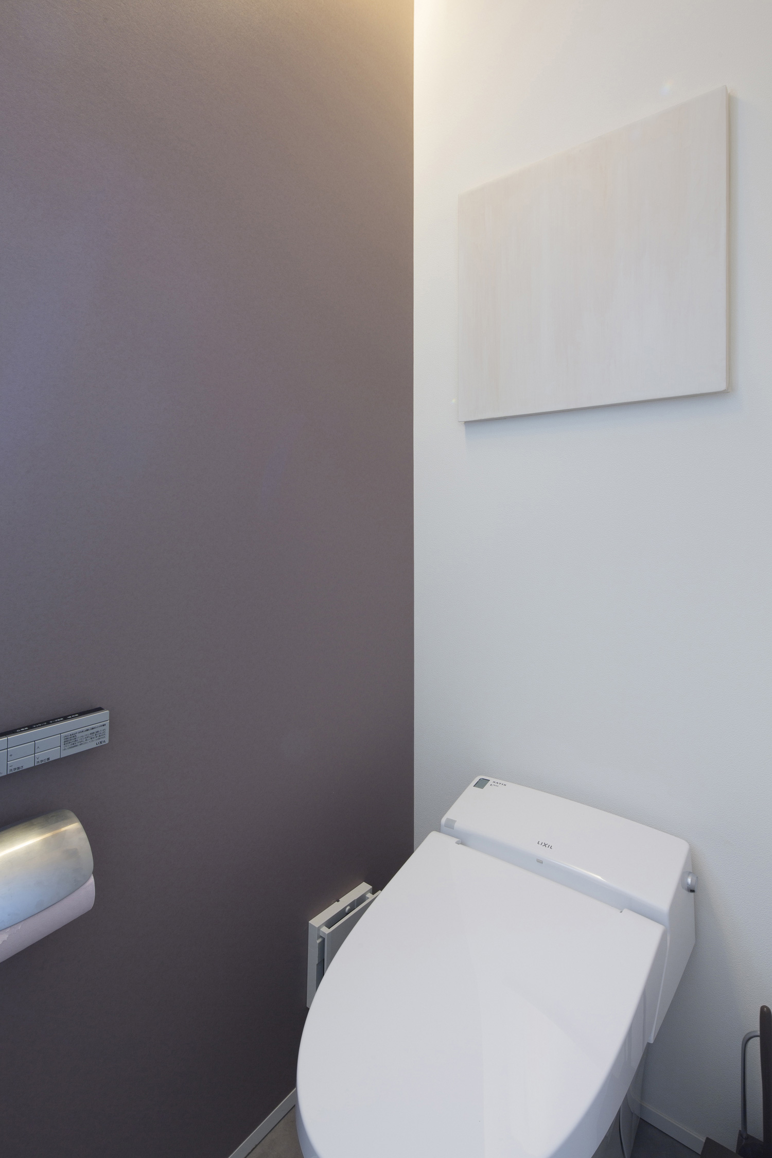 黒いアクセントクロスがあるモノトーンですっきりとしたトイレ・デザイン住宅