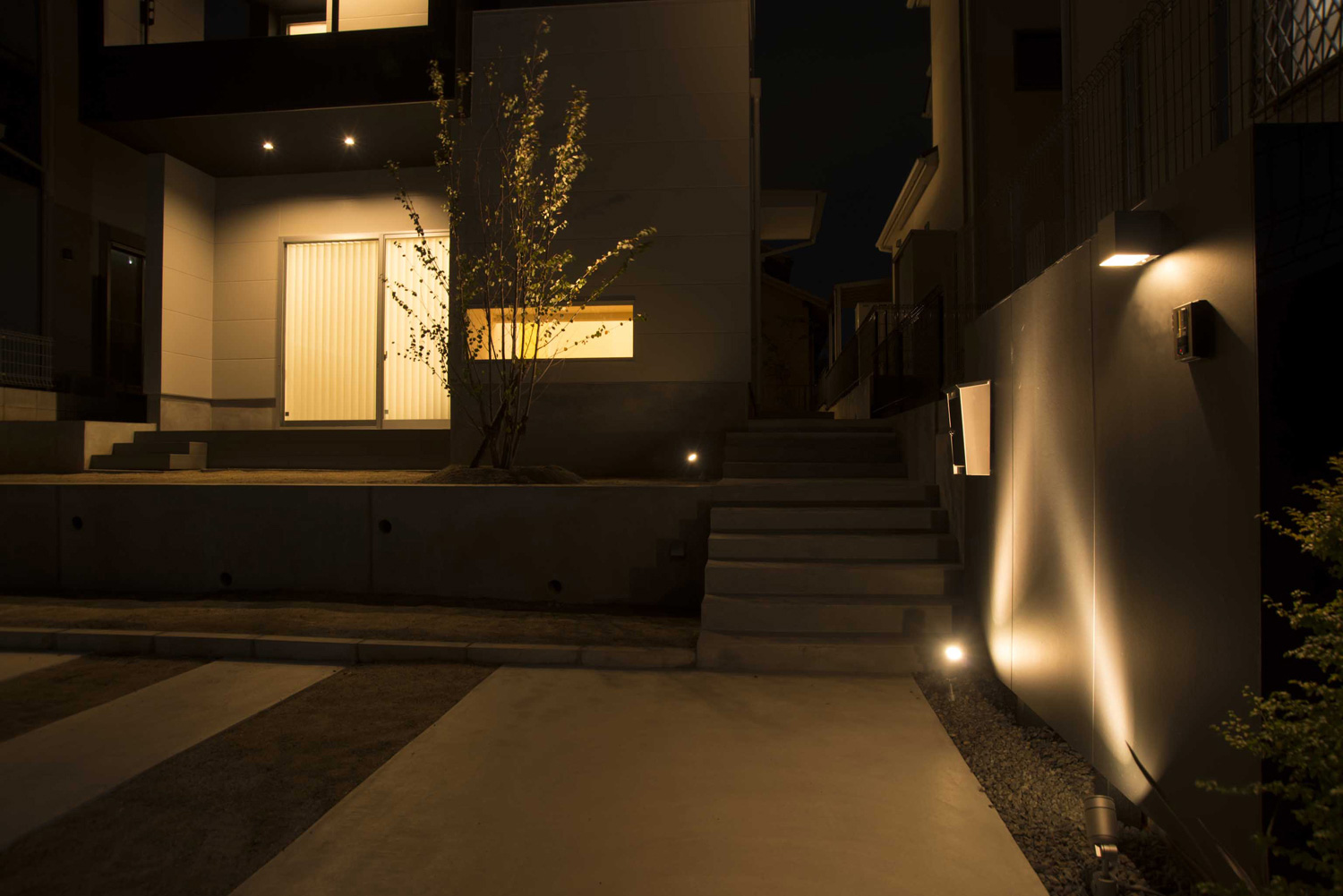 玄関の壁が照明に照らされる家の外観・デザイン住宅