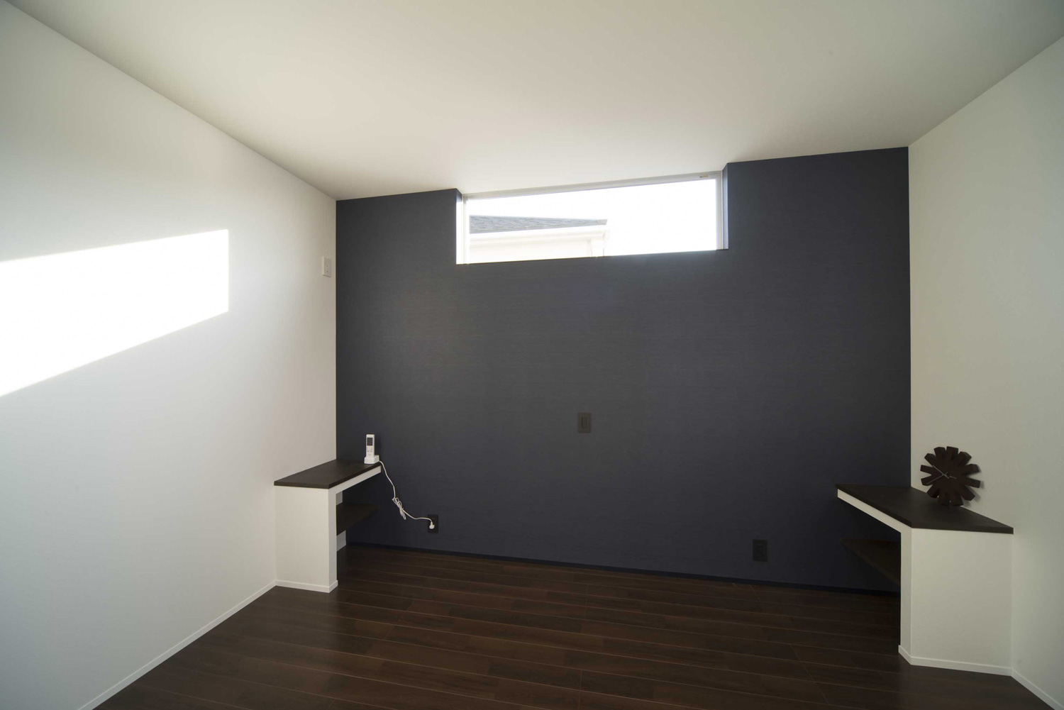 アクセントクロスの天井近くにスリット窓を取り付けたシンプルな寝室・デザイン住宅