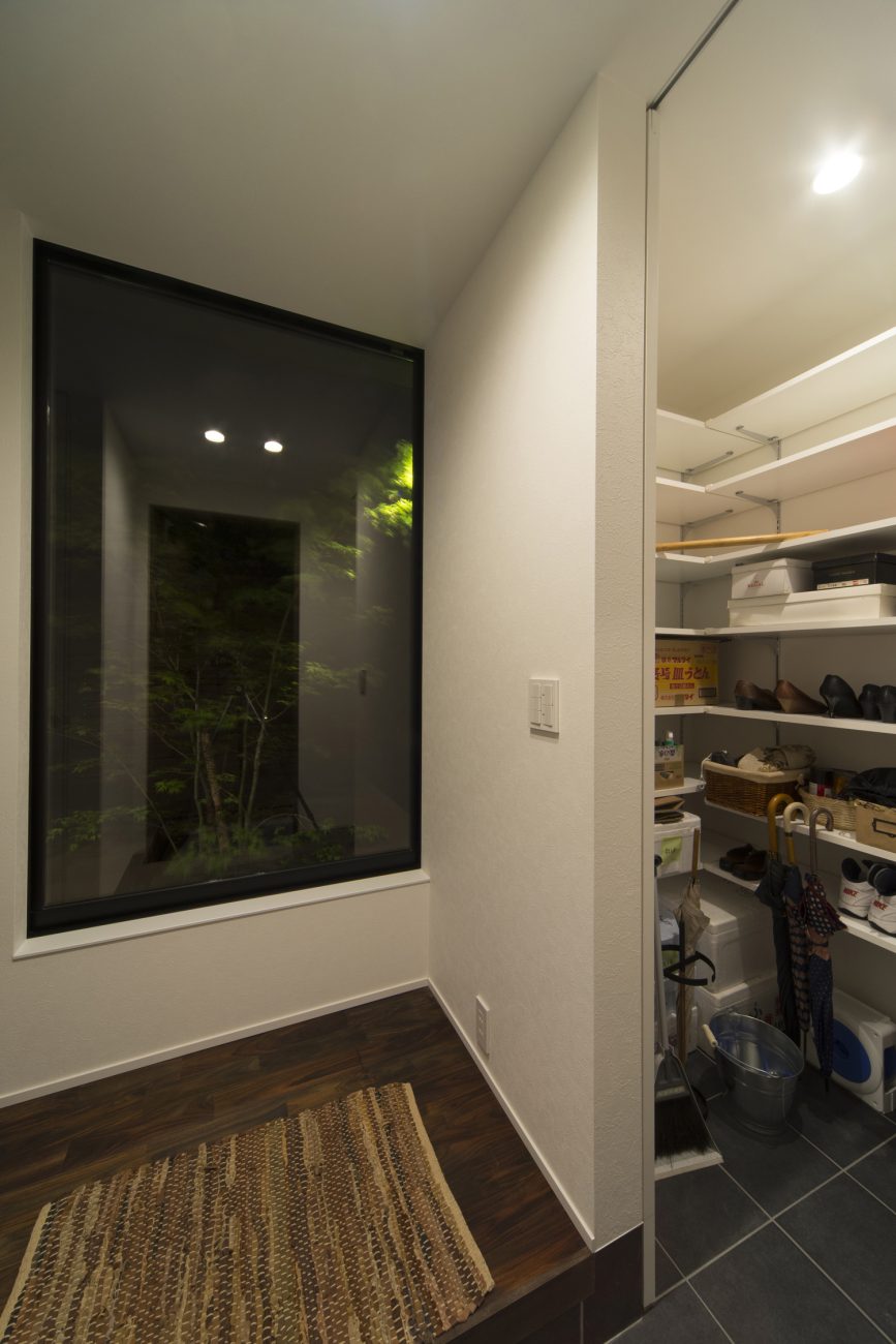 正面に大きな窓があるシューズインクローゼットを取り付けた玄関・デザイン住宅