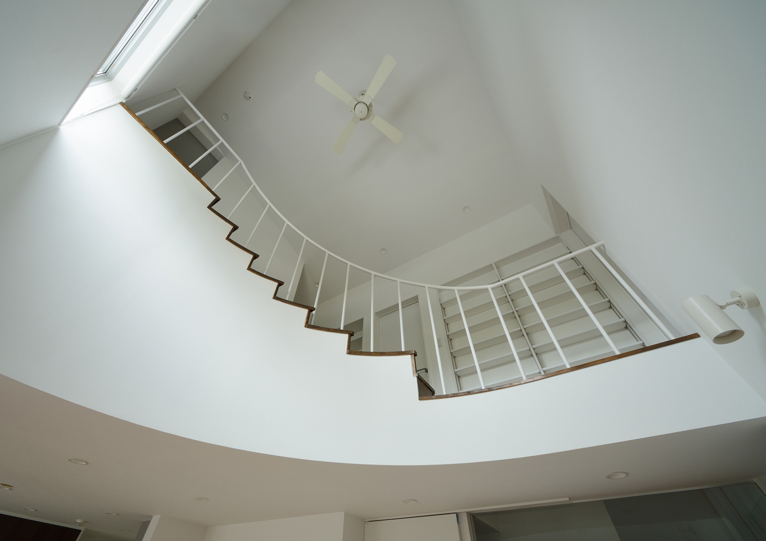 アーチ壁に沿って階段がある吹き抜けのLDK・デザイン住宅