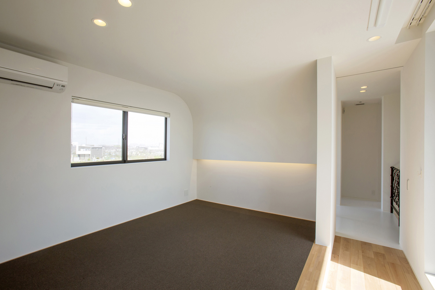 カーペットの床で壁が丸くなっているおしゃれな寝室・デザイン住宅